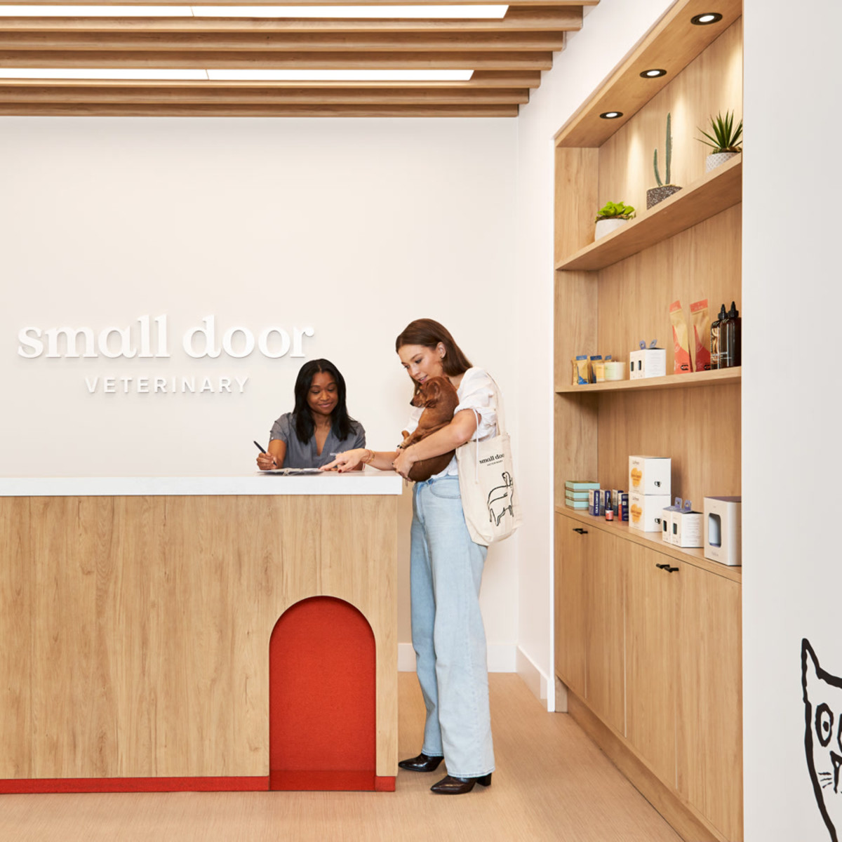 A pet owner and Small Door staff member with a dog at a bright clinic reception desk