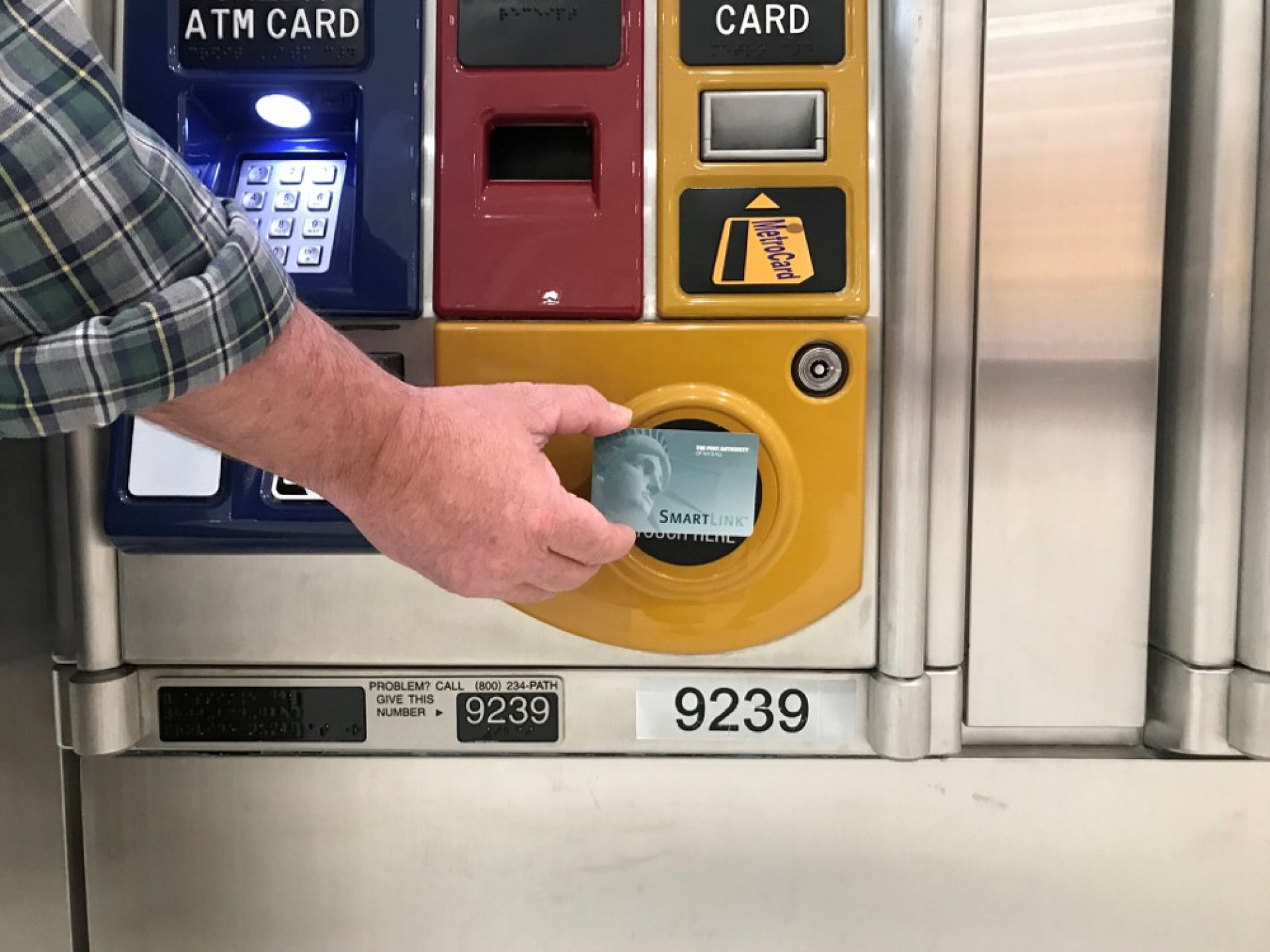 A passenger holds a SmartLink card against the circular target on a PATH ticket vending machine