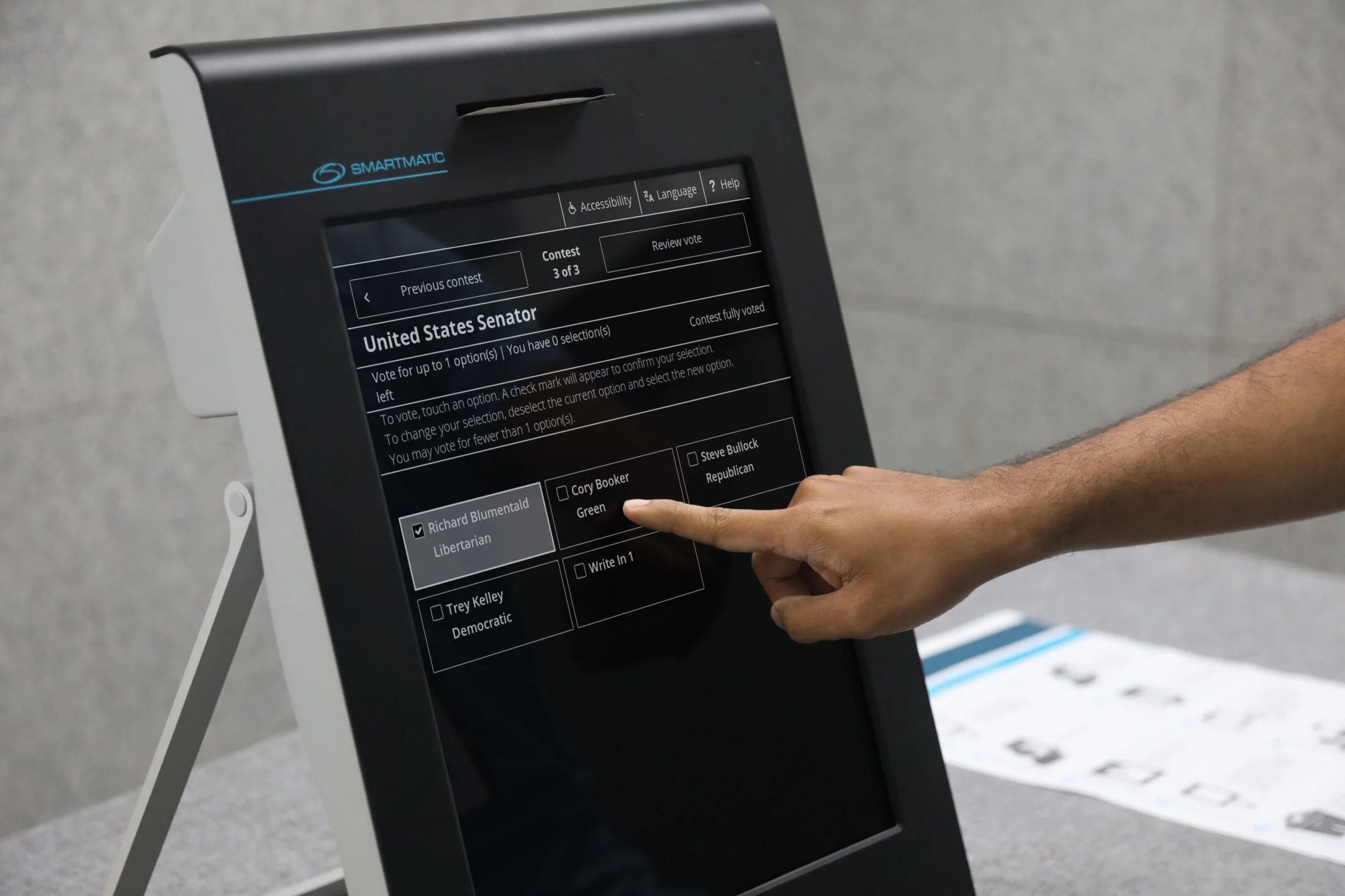 A demonstration voter selects an option on a Smartmatic touchscreen with language and accessibility menus