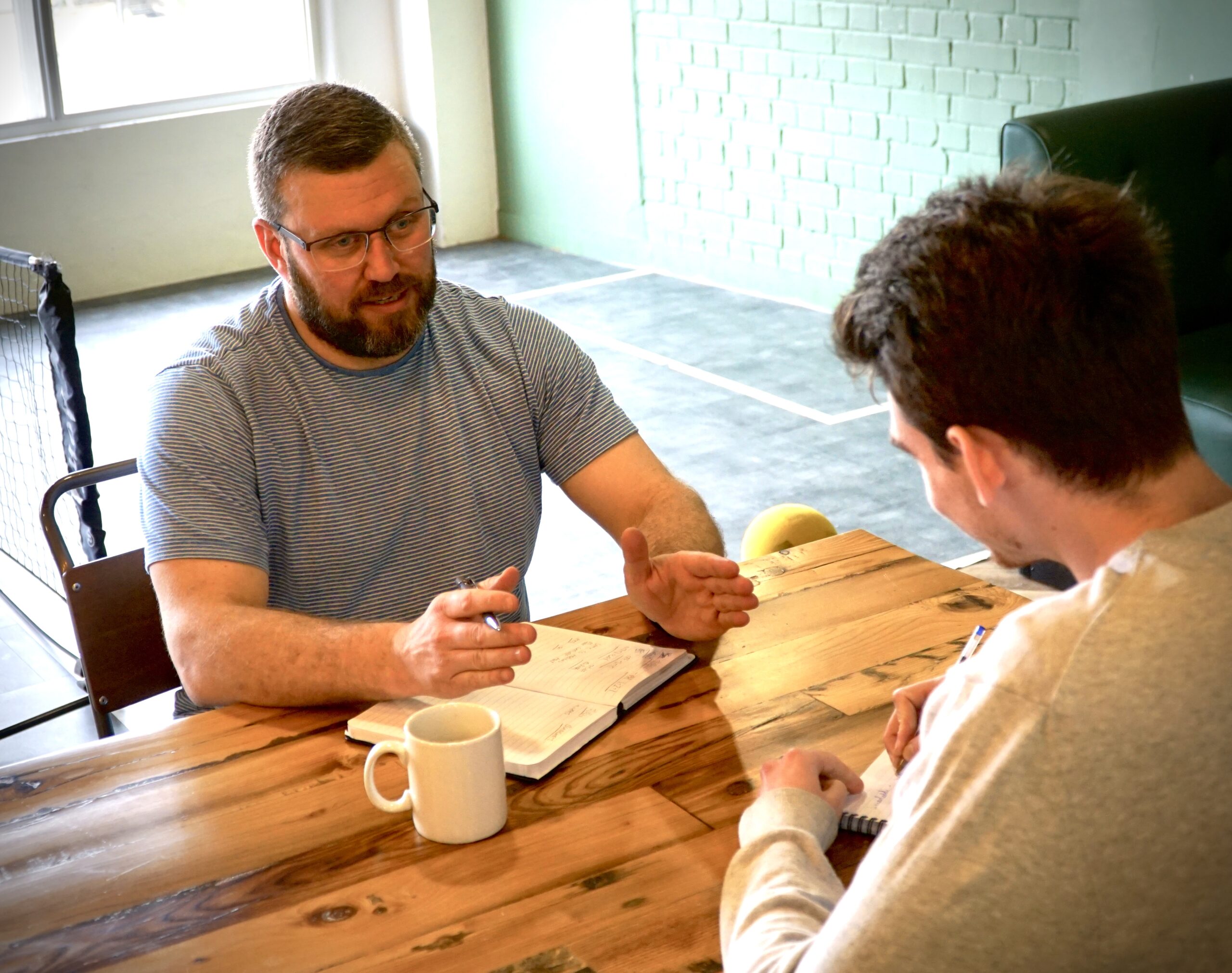 Two people discussing notes at a wooden table in a Smartodds office photograph