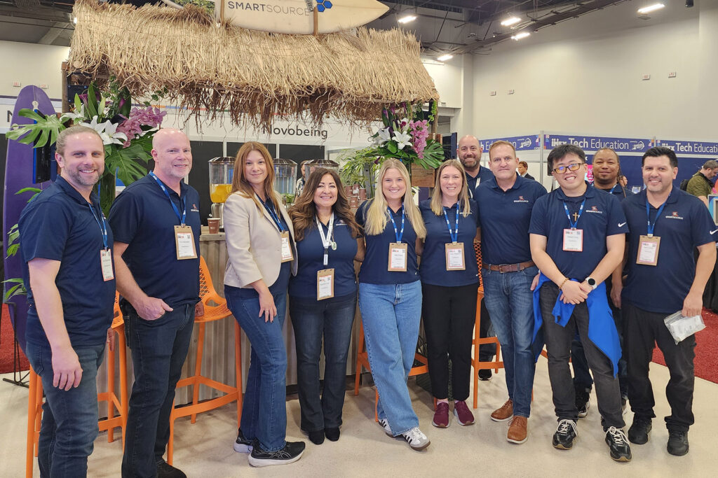 SmartSource team members together at a trade show booth with a thatched canopy