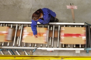 Company-supplied photograph of a worker handling parcels on a warehouse conveyor