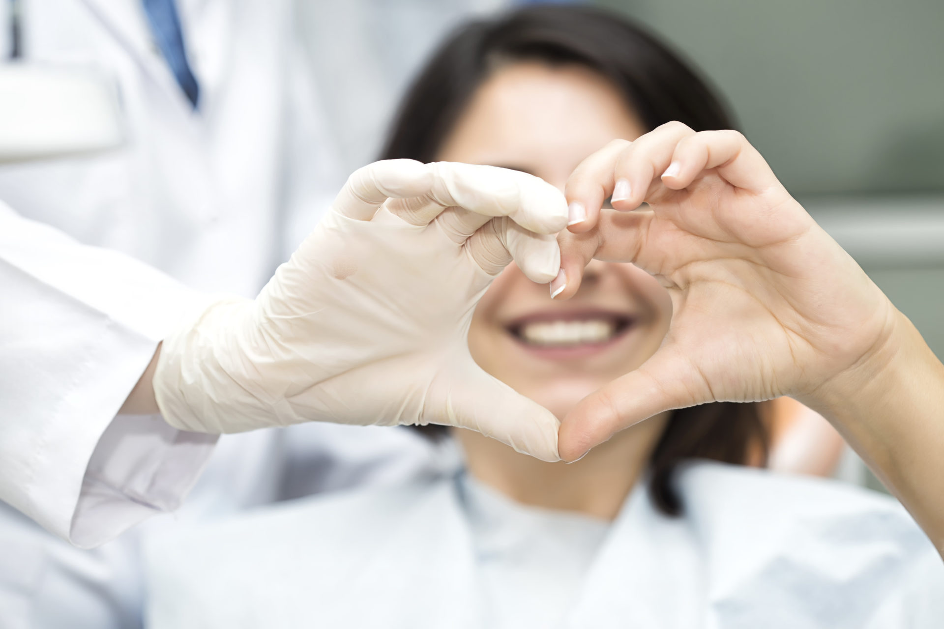 A dental clinician and patient make a heart shape with their hands