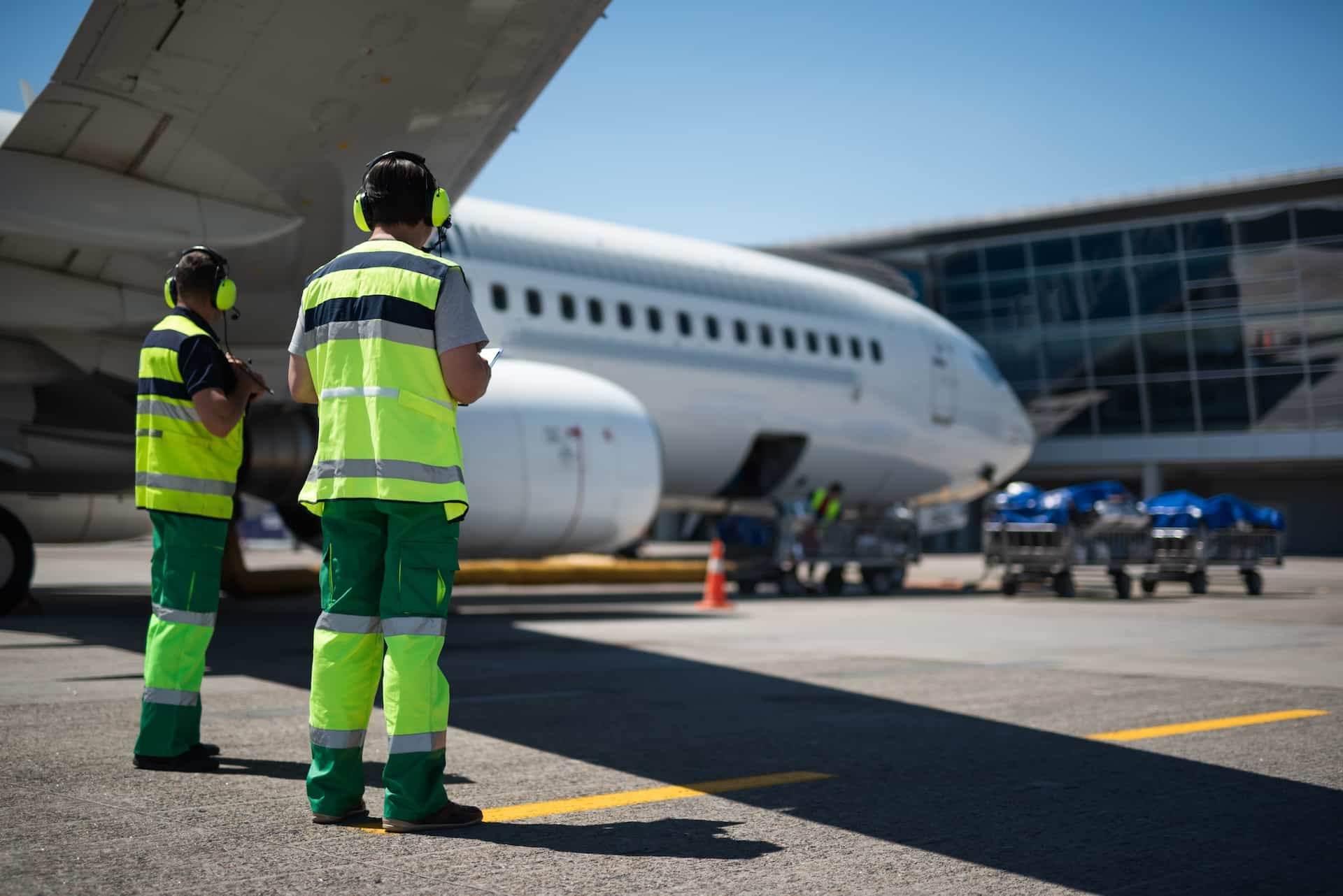 Airport ground crew standing beside a passenger aircraft
