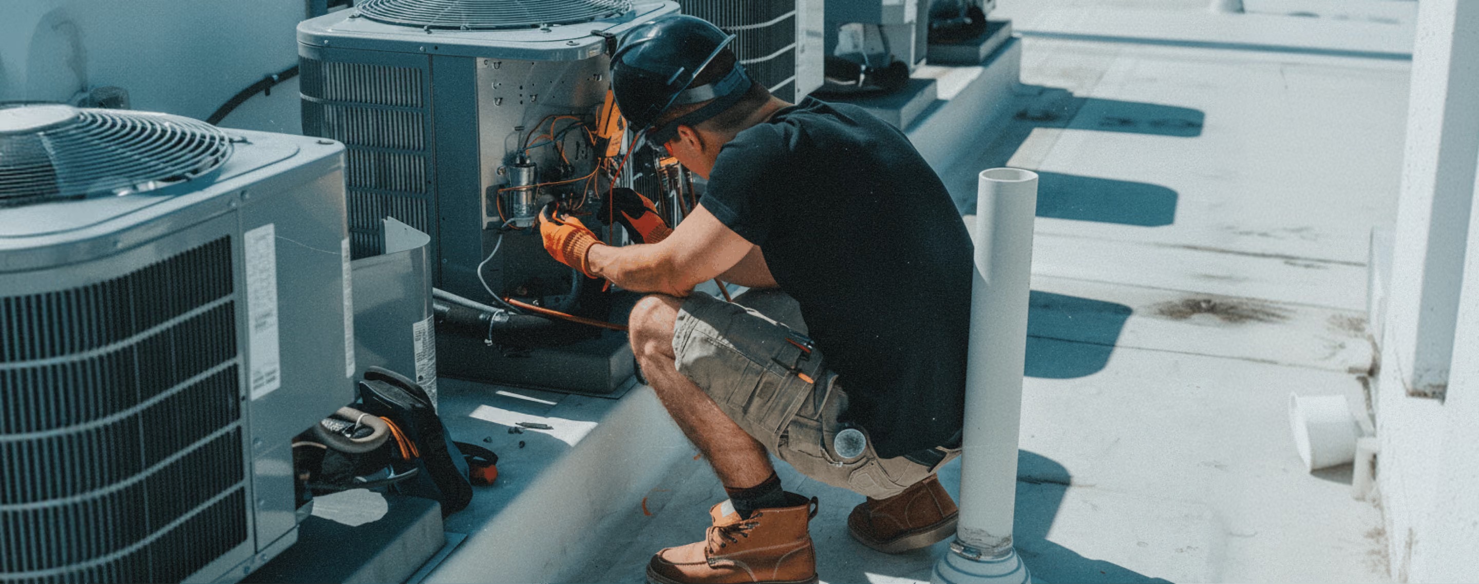 Lessen promotional photograph showing a technician working on rooftop HVAC equipment