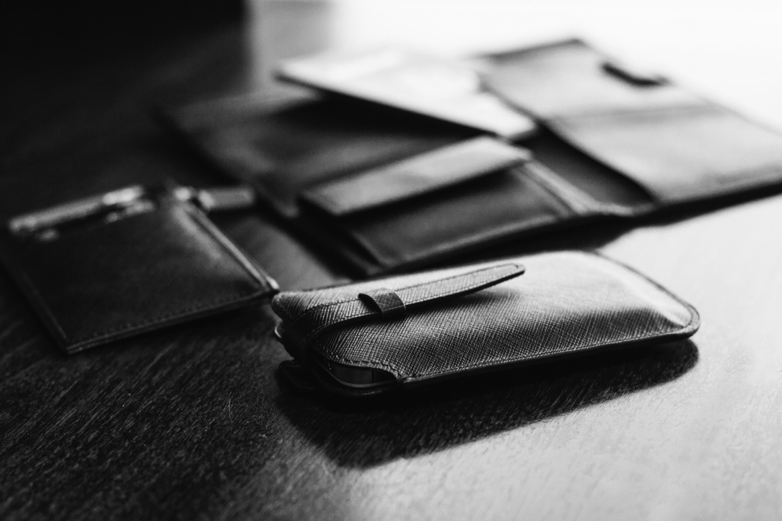Black-and-white product photograph of textured wallets and small cases from the company gift portfolio