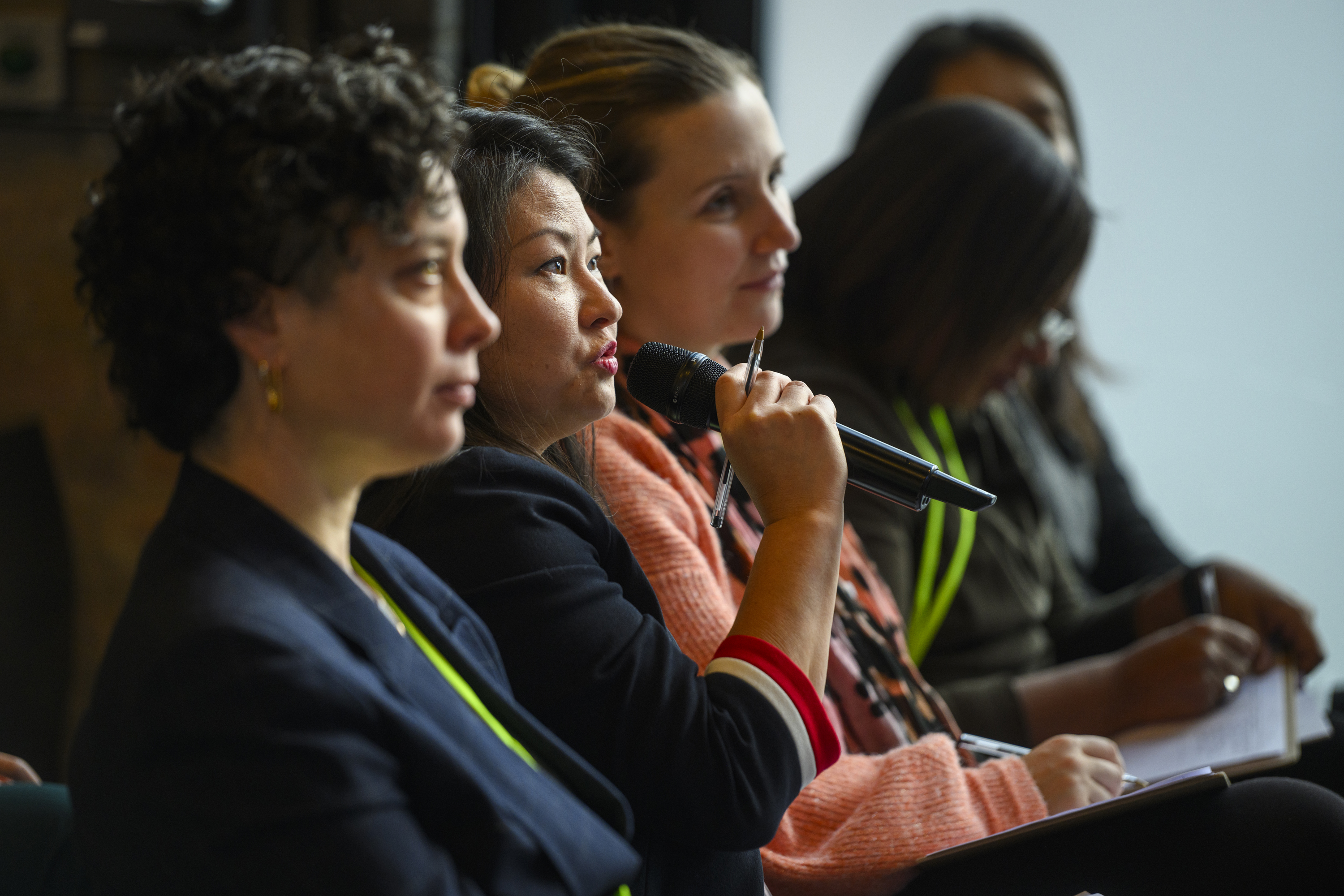 Participants listening as a speaker holds a microphone during a Social Tech Trust event
