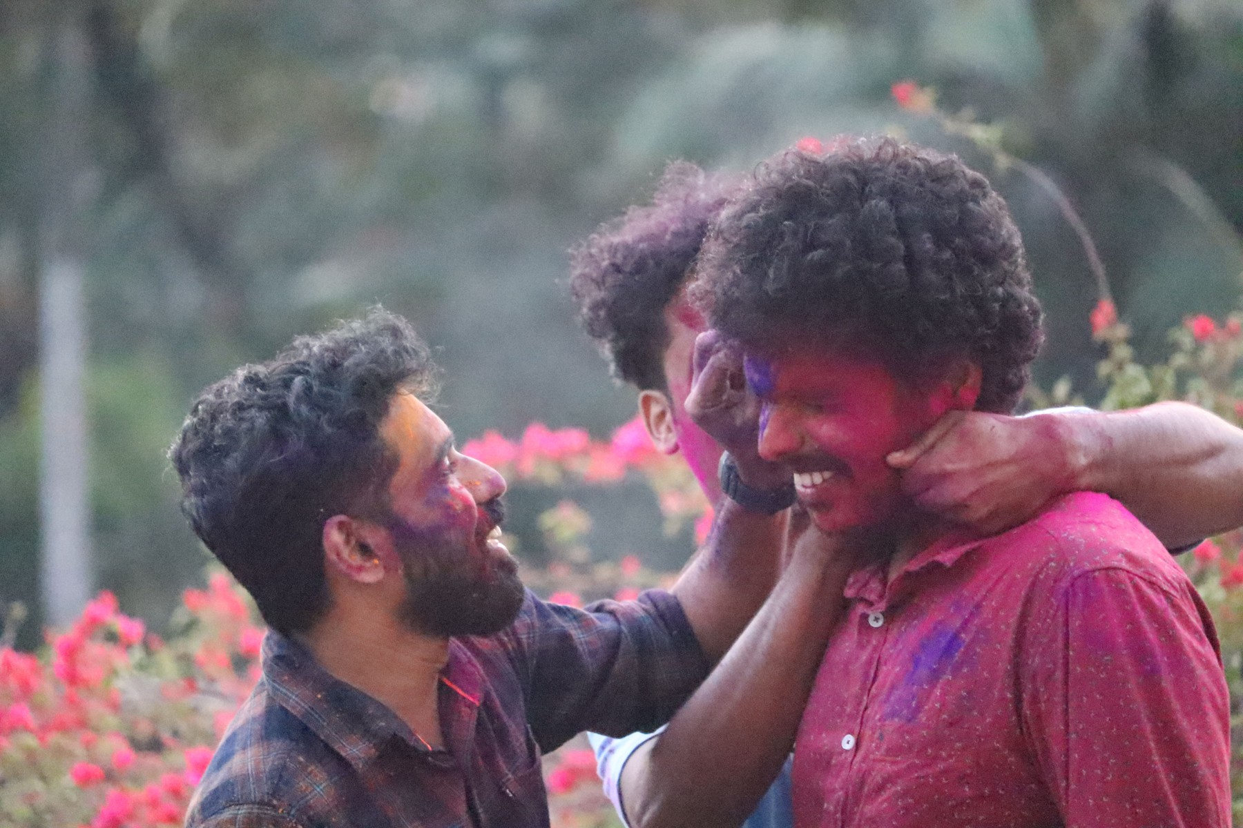 People smiling as colored powder is applied during a Socius staff celebration