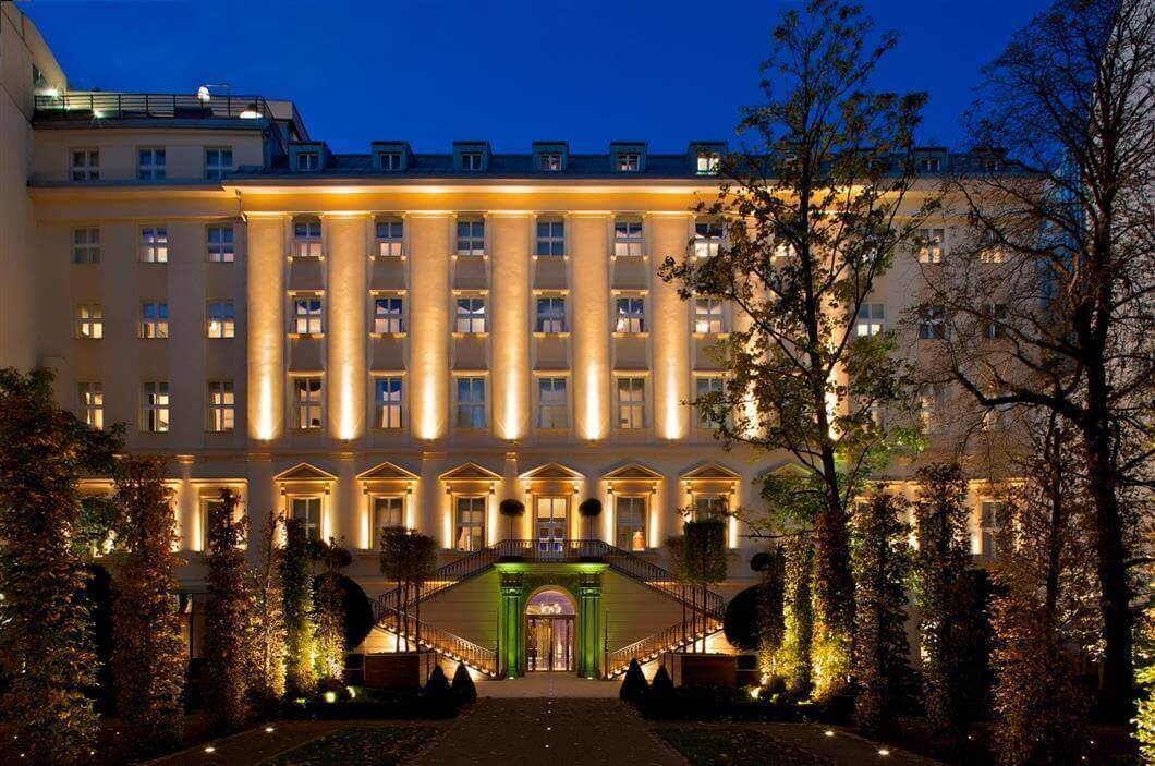 The illuminated courtyard facade of The Grand Mark Prague at dusk