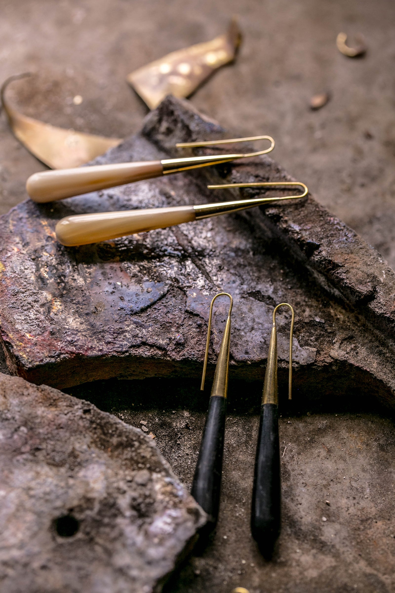 SOKO gold-toned earrings arranged on a dark artisan work surface