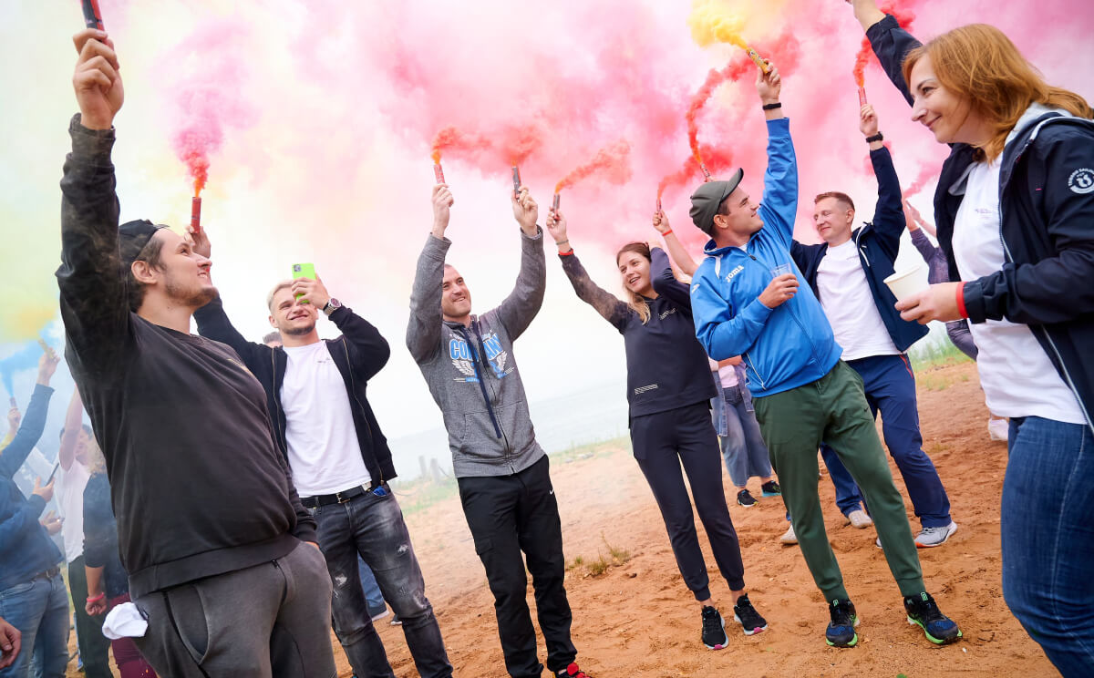 Solbeg team members outdoors holding colorful smoke flares