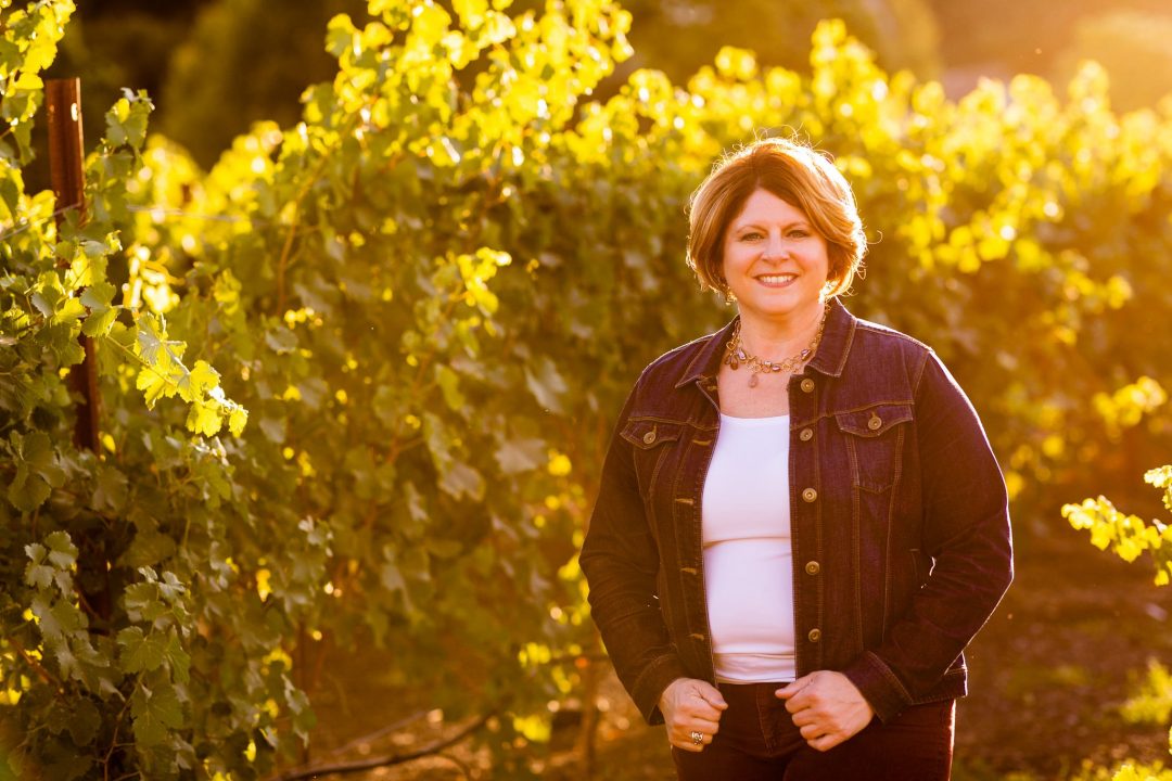 Solterra Strategies founder Stacie Jacob standing between sunlit vineyard rows
