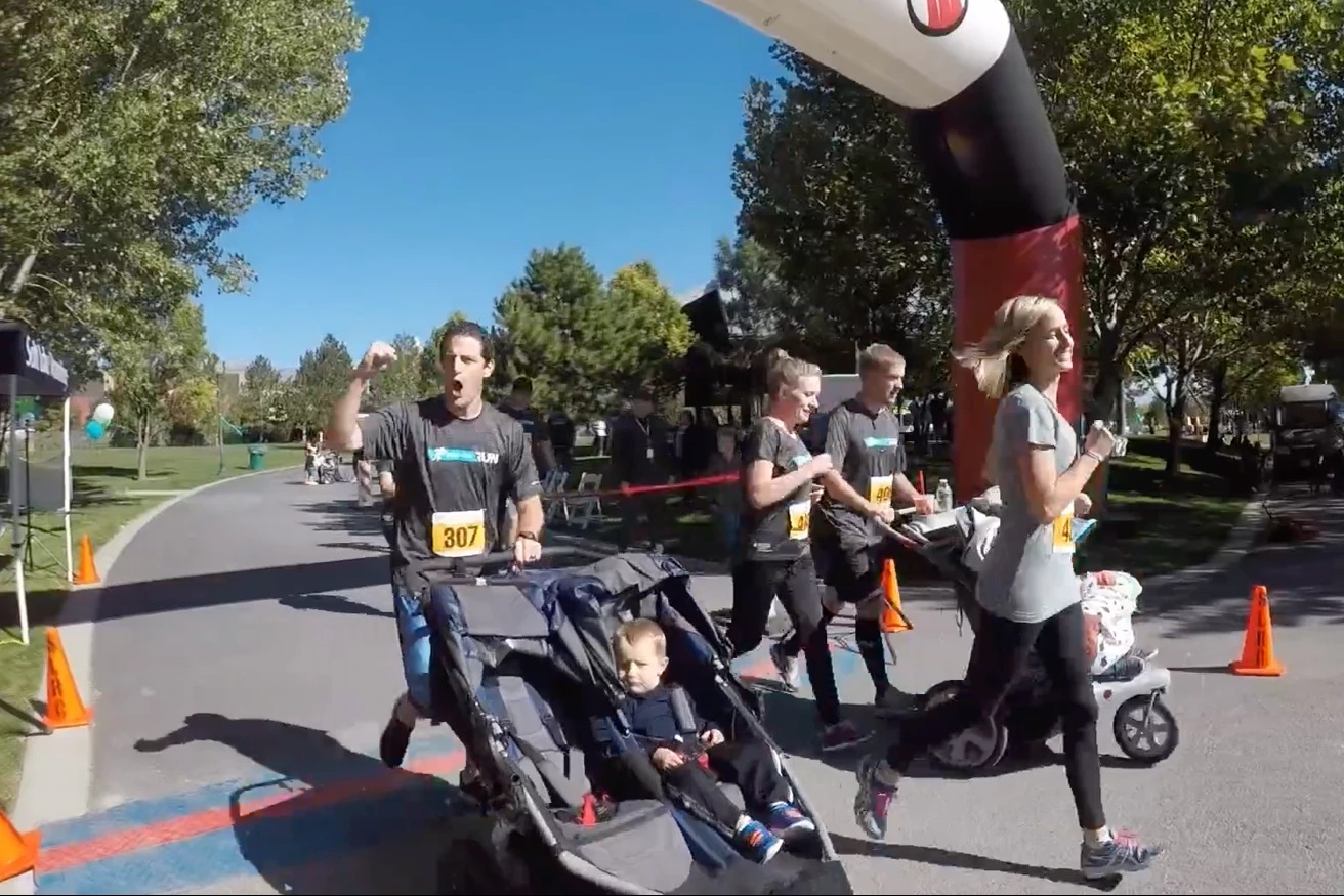 Participants wearing Solutionreach shirts at an outdoor community event, some pushing strollers