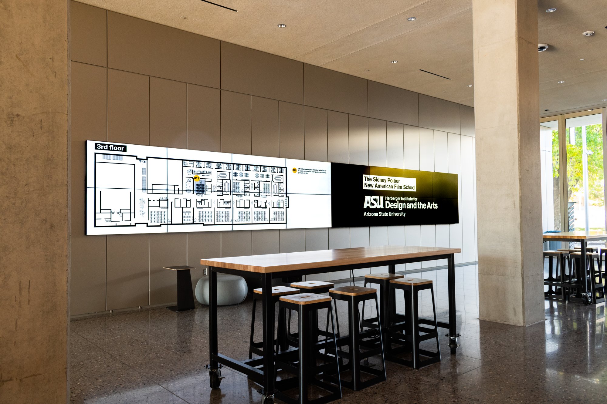 Wall-mounted digital wayfinding displays above tables at Arizona State University’s MIX Center