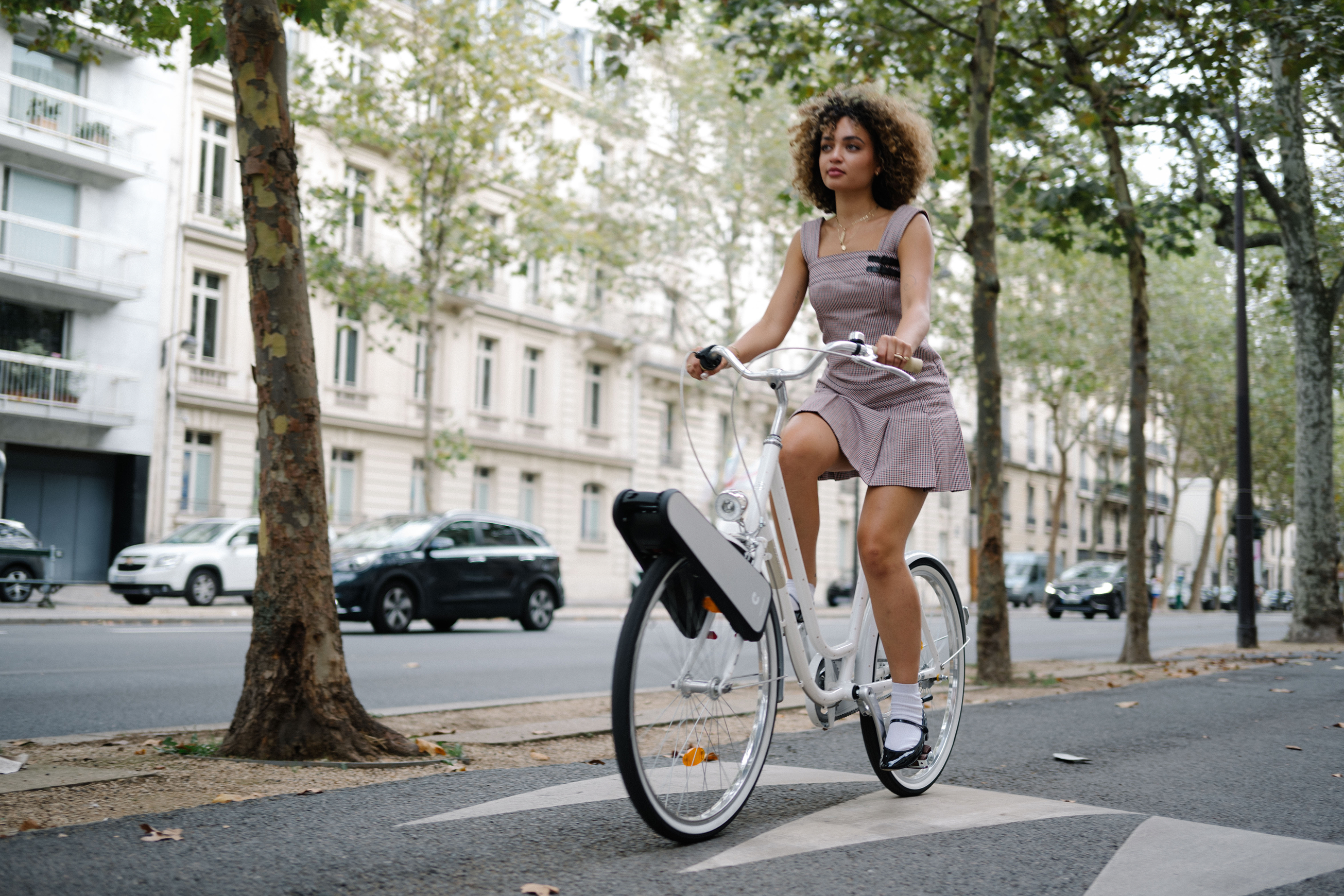 A cyclist rides a white bicycle with a CLIP motor attached above the front wheel