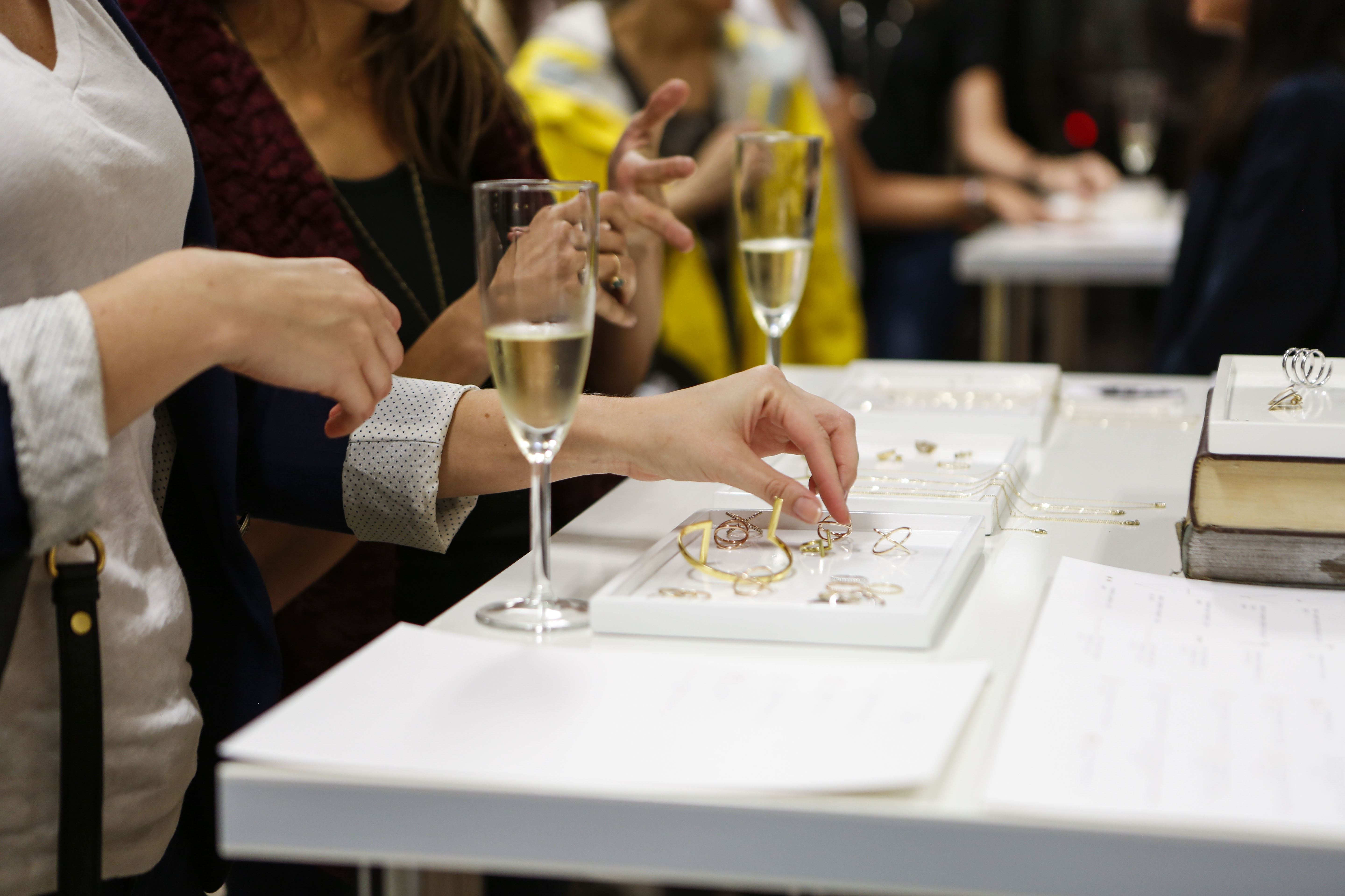 Customers examining rings and necklaces laid out on white trays at an early Aurate SoHo pop-up