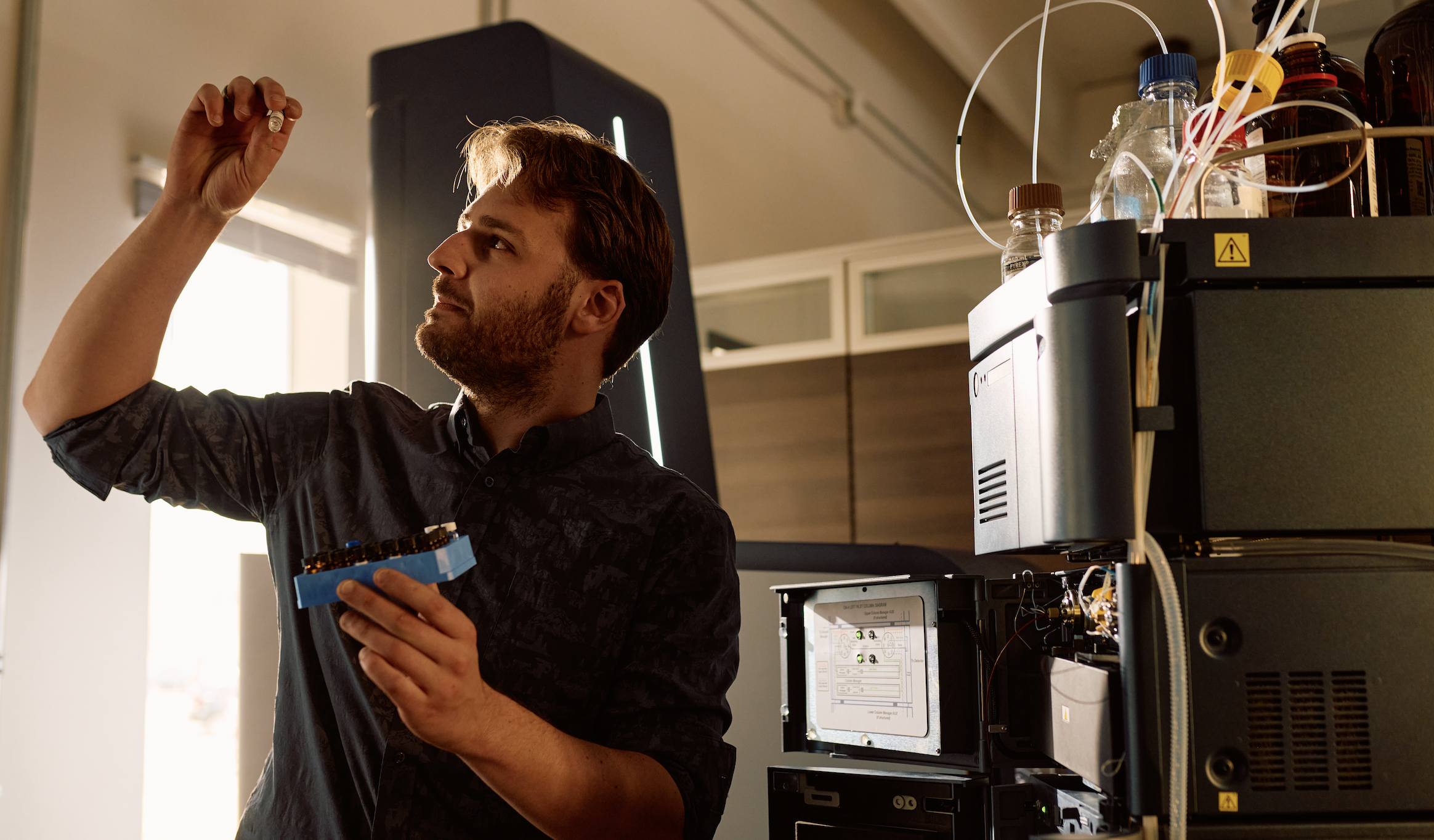 An Enveda scientist examines a sample beside mass spectrometry equipment