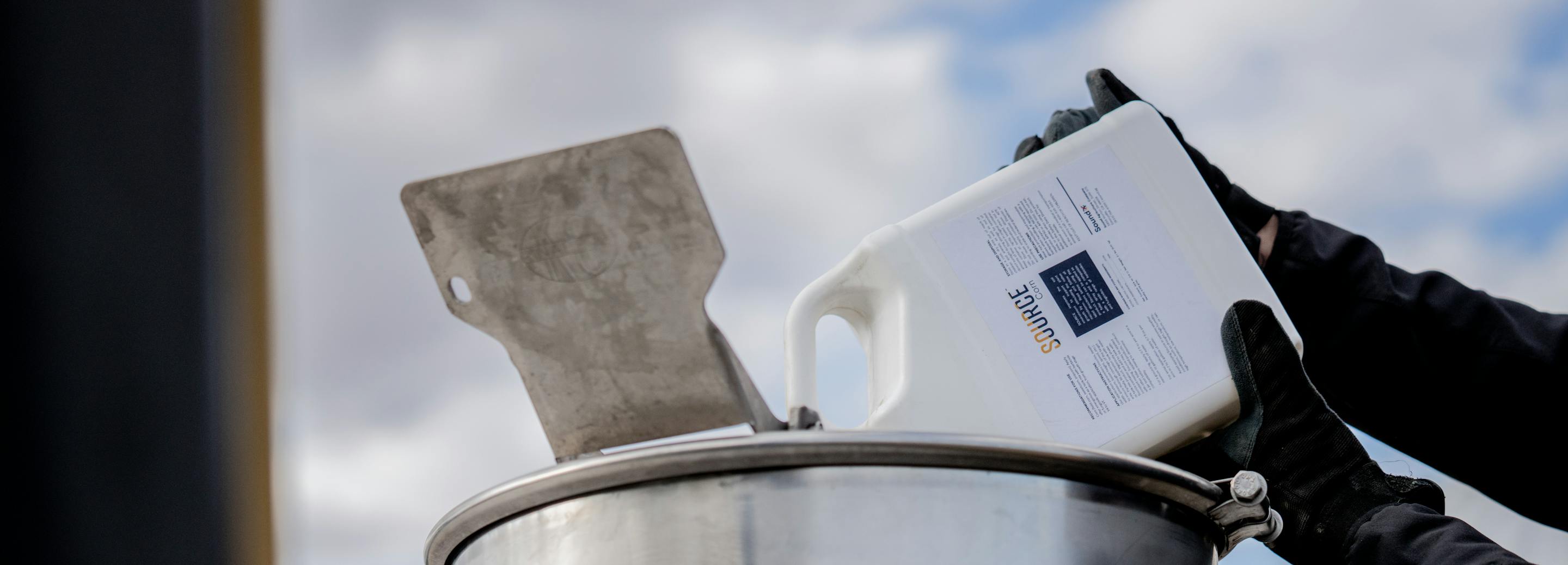 A grower pours a Sound Agriculture SOURCE product into a farm mixing tank