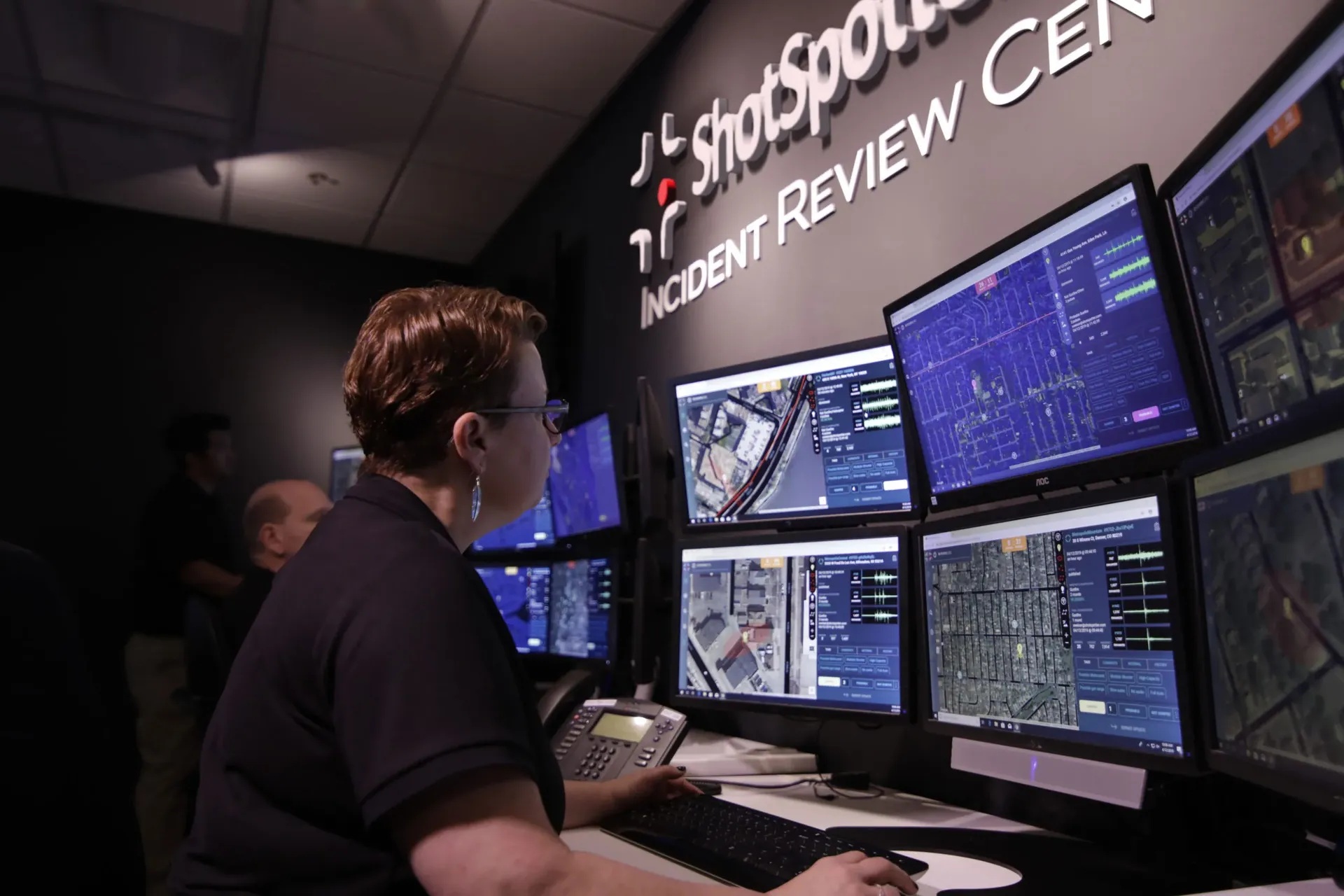 A ShotSpotter reviewer at multiple screens showing maps and acoustic waveforms in the Incident Review Center