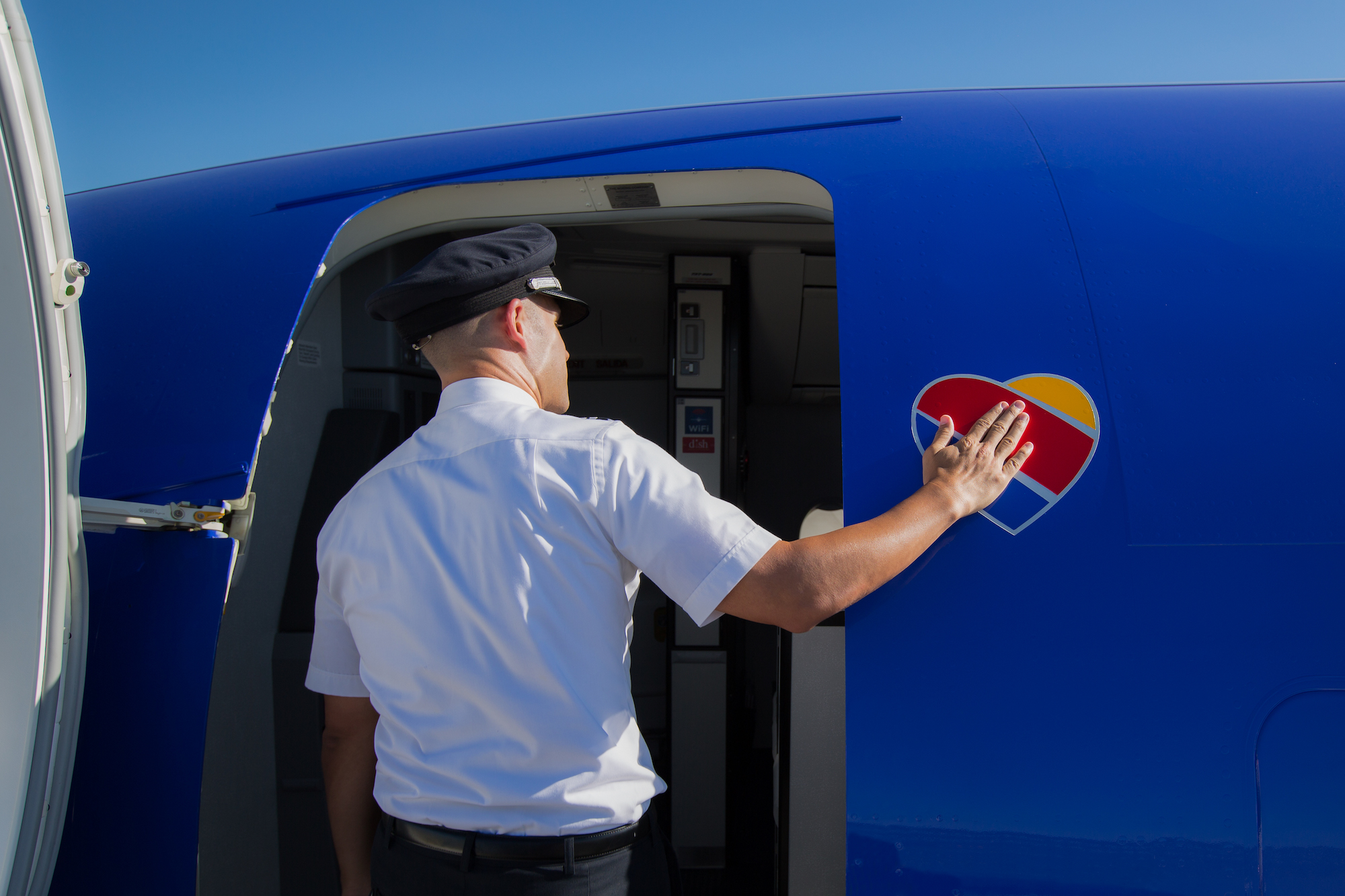 A Southwest pilot boards a blue aircraft with a hand on its heart emblem