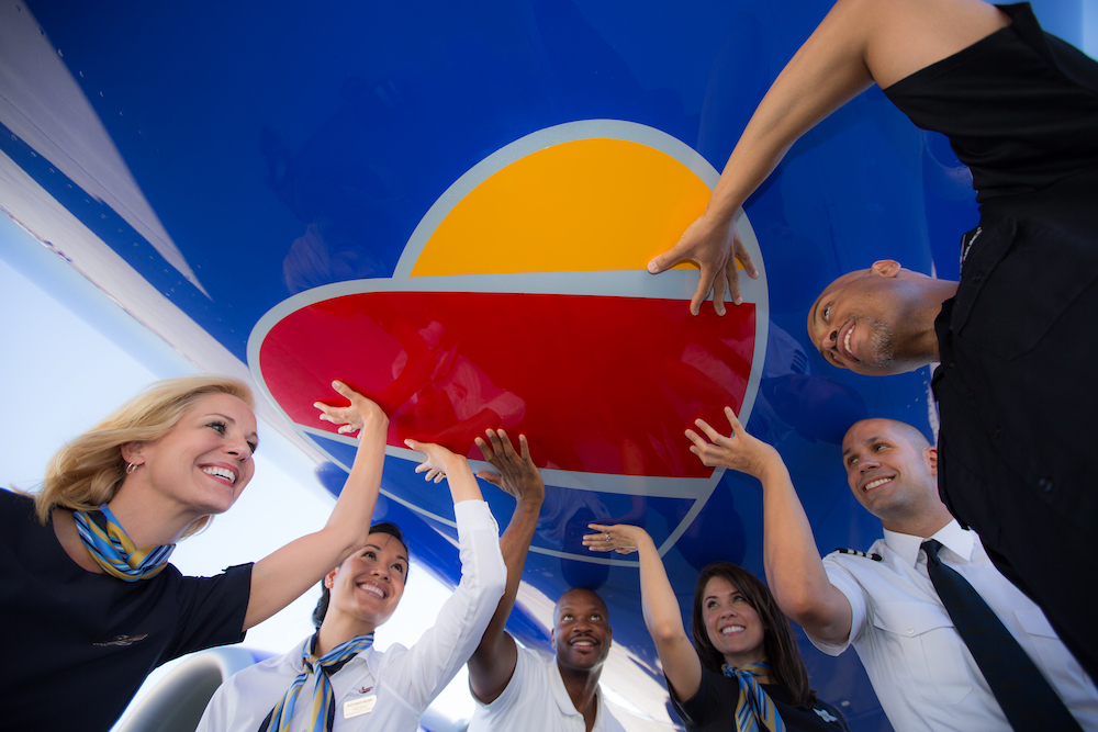 Southwest employees reach toward the large heart emblem beneath a plane