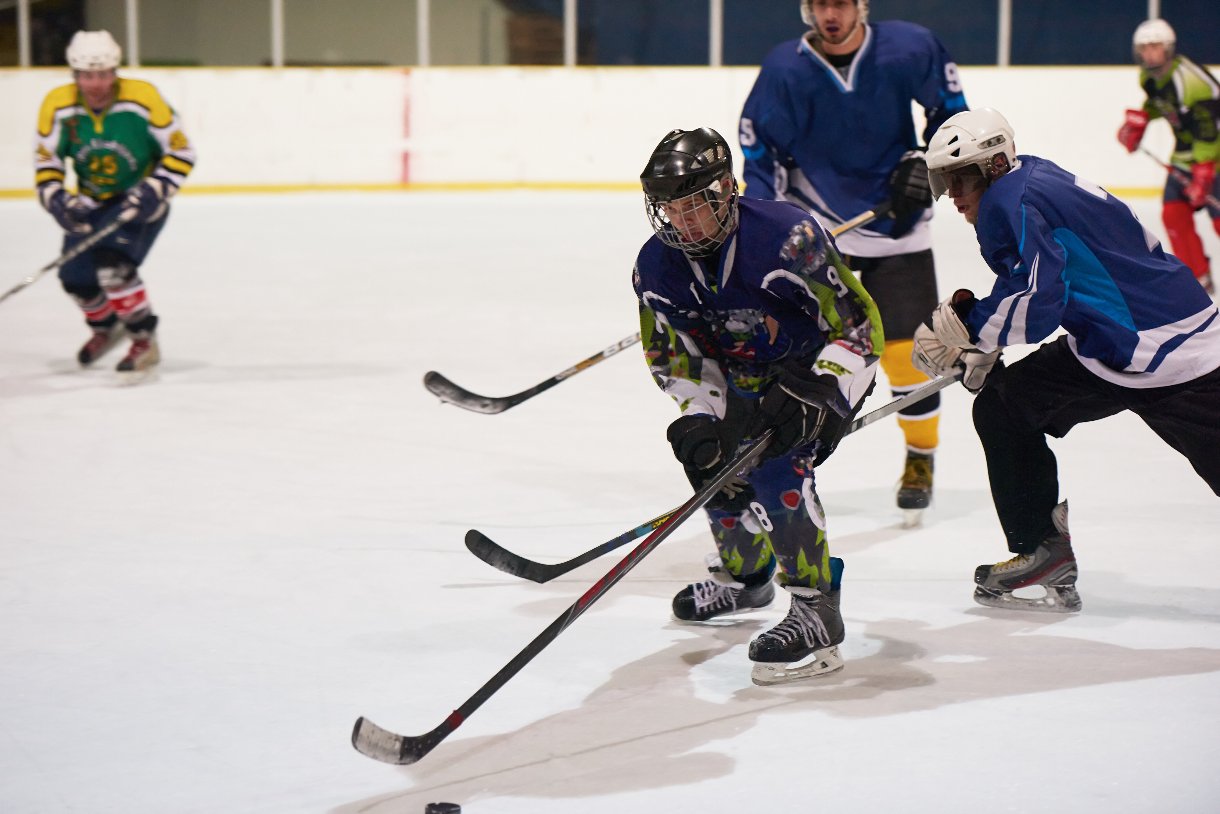 Ice hockey players contesting possession on an indoor rink