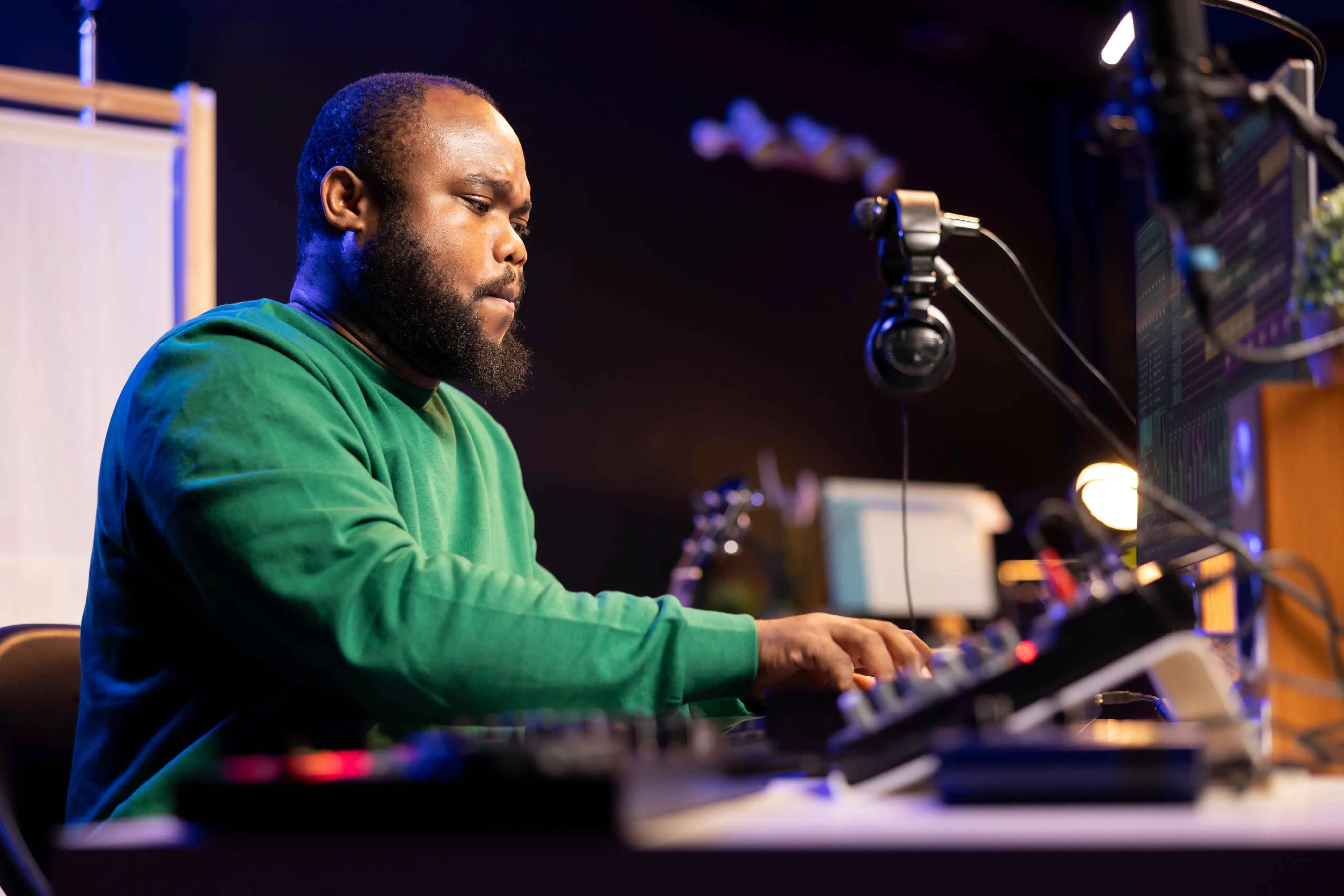 A person working at an audio console with a microphone and monitor, pictured on Spalk’s remote studio page