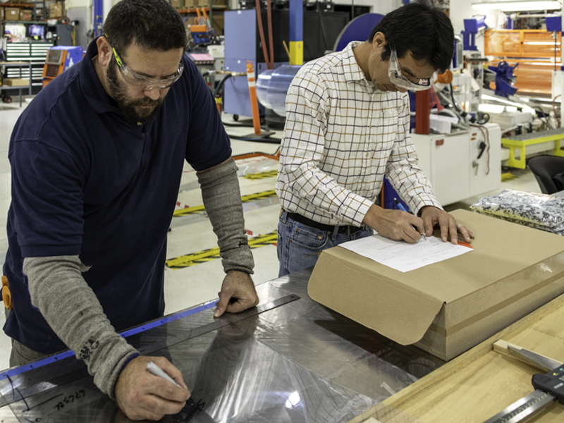 Two people measuring material and recording work at Spartech’s Innovation Center