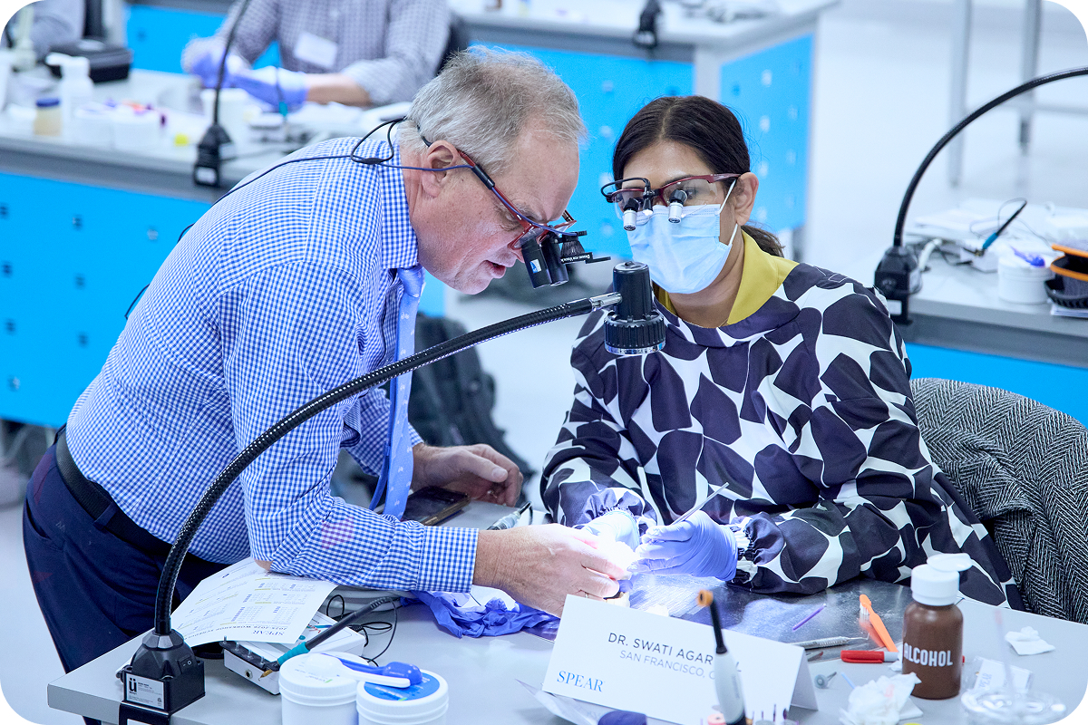 An instructor guides a participant through a dental model exercise at a Spear workshop