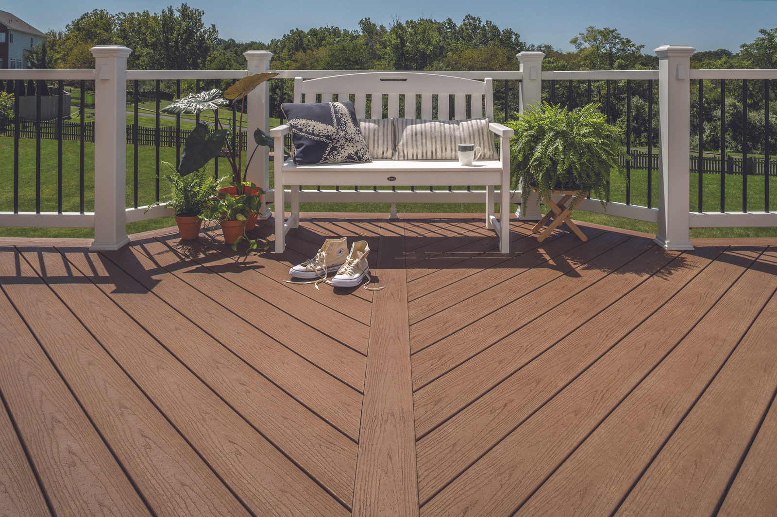 Trex composite decking with white posts, black railing and a garden bench