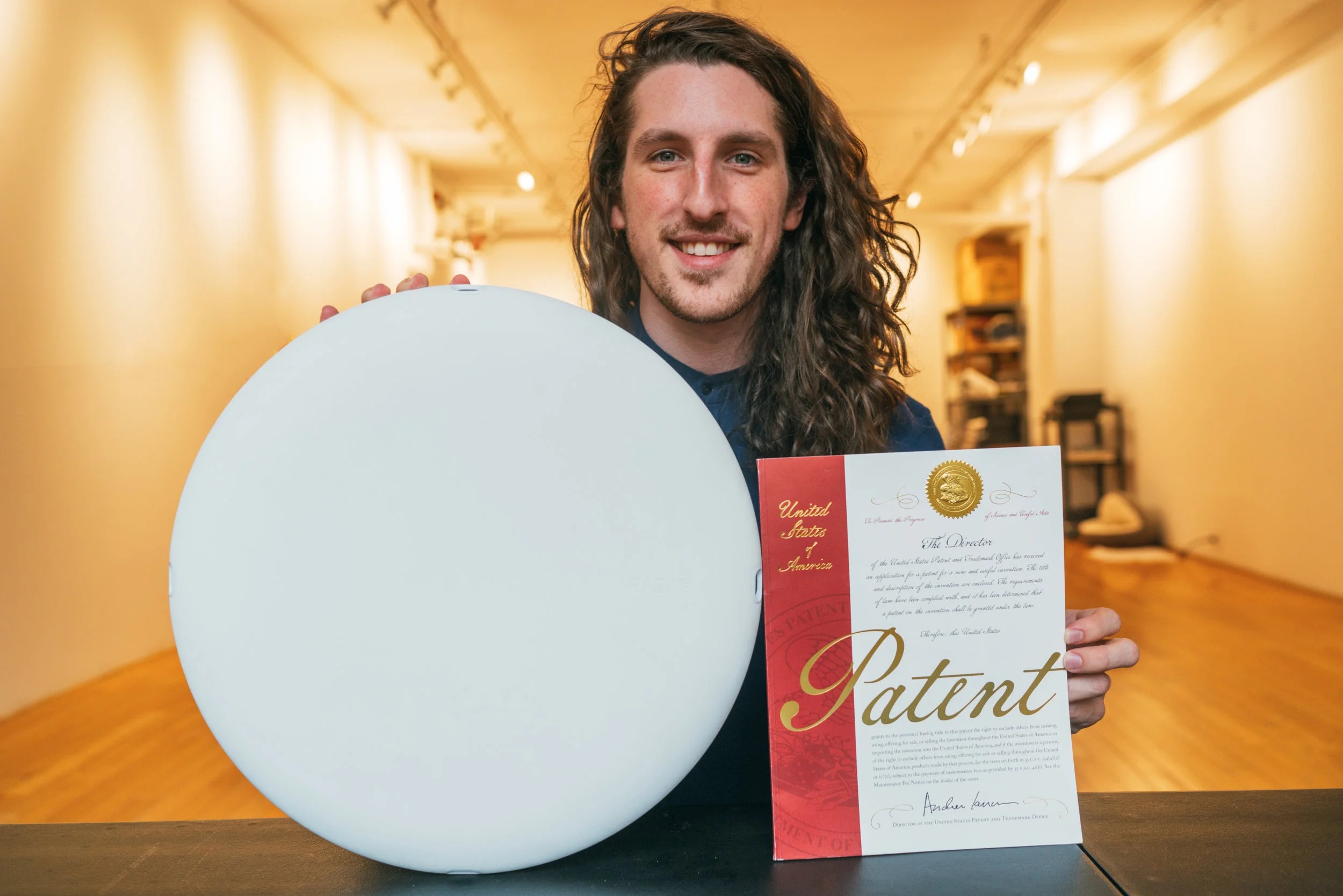 Spencer Hewett, founder and CEO of RADAR, holding a ceiling sensor and a patent certificate