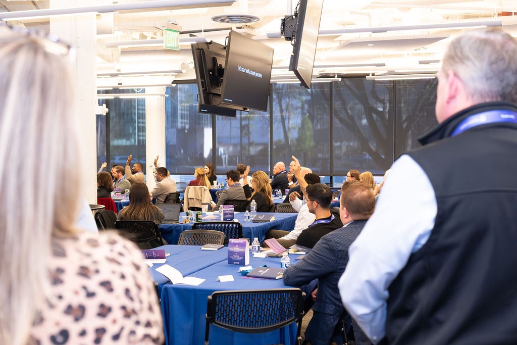 Procurement professionals raising their hands during a SpendHQ Insights Summit session