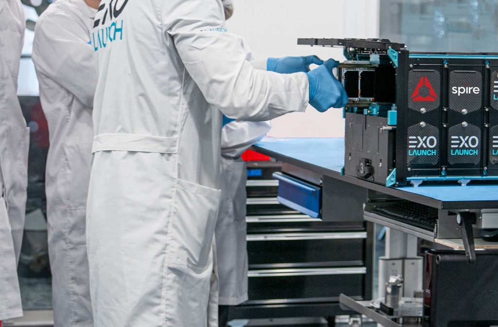 Gloved technicians integrating a compact Spire satellite into launch hardware