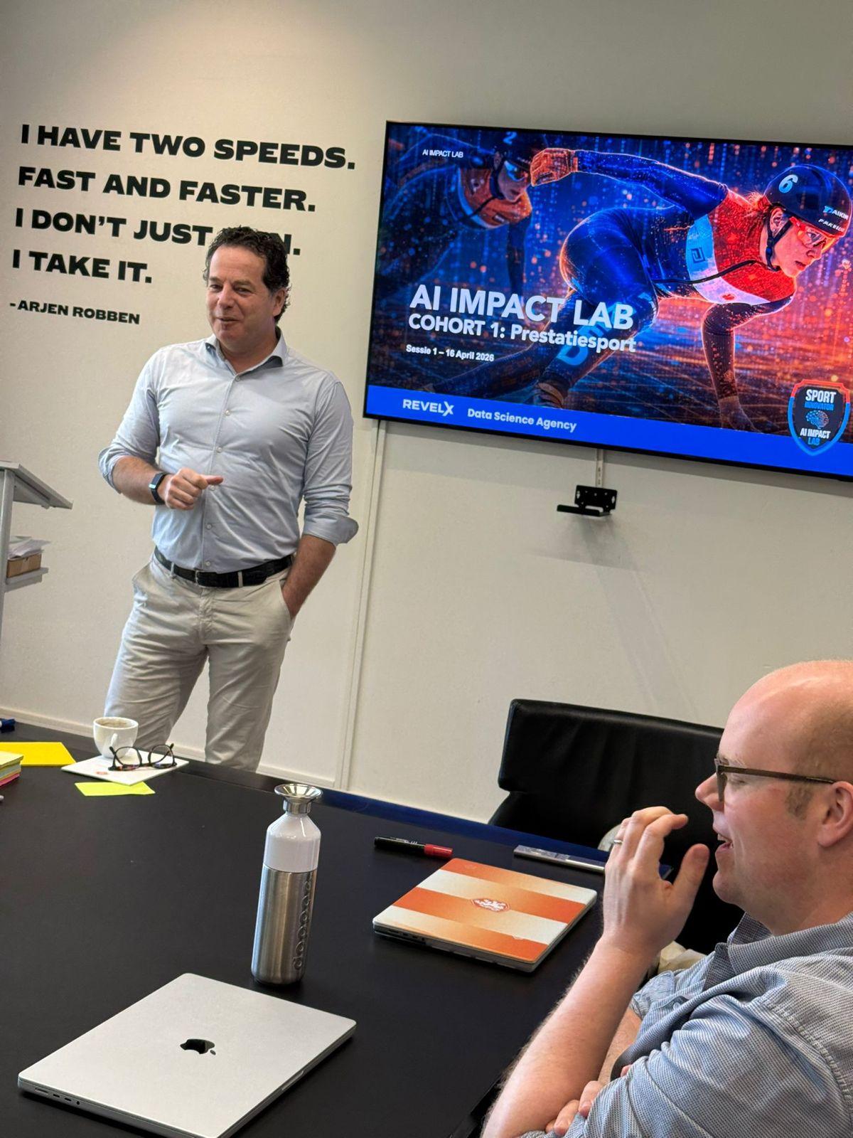 An AI Impact Lab presenter addressing workshop participants beside a screen