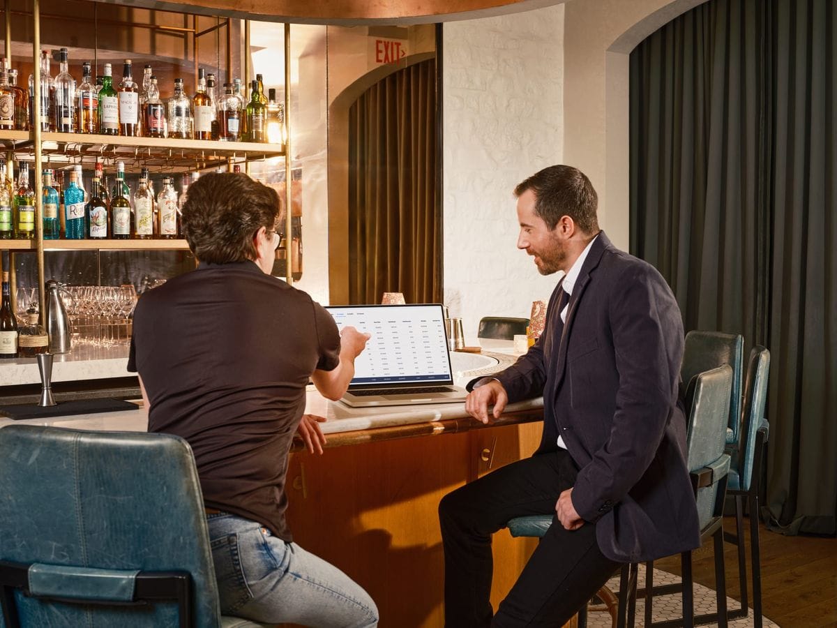 A restaurant operator reviews business information on a laptop at the bar