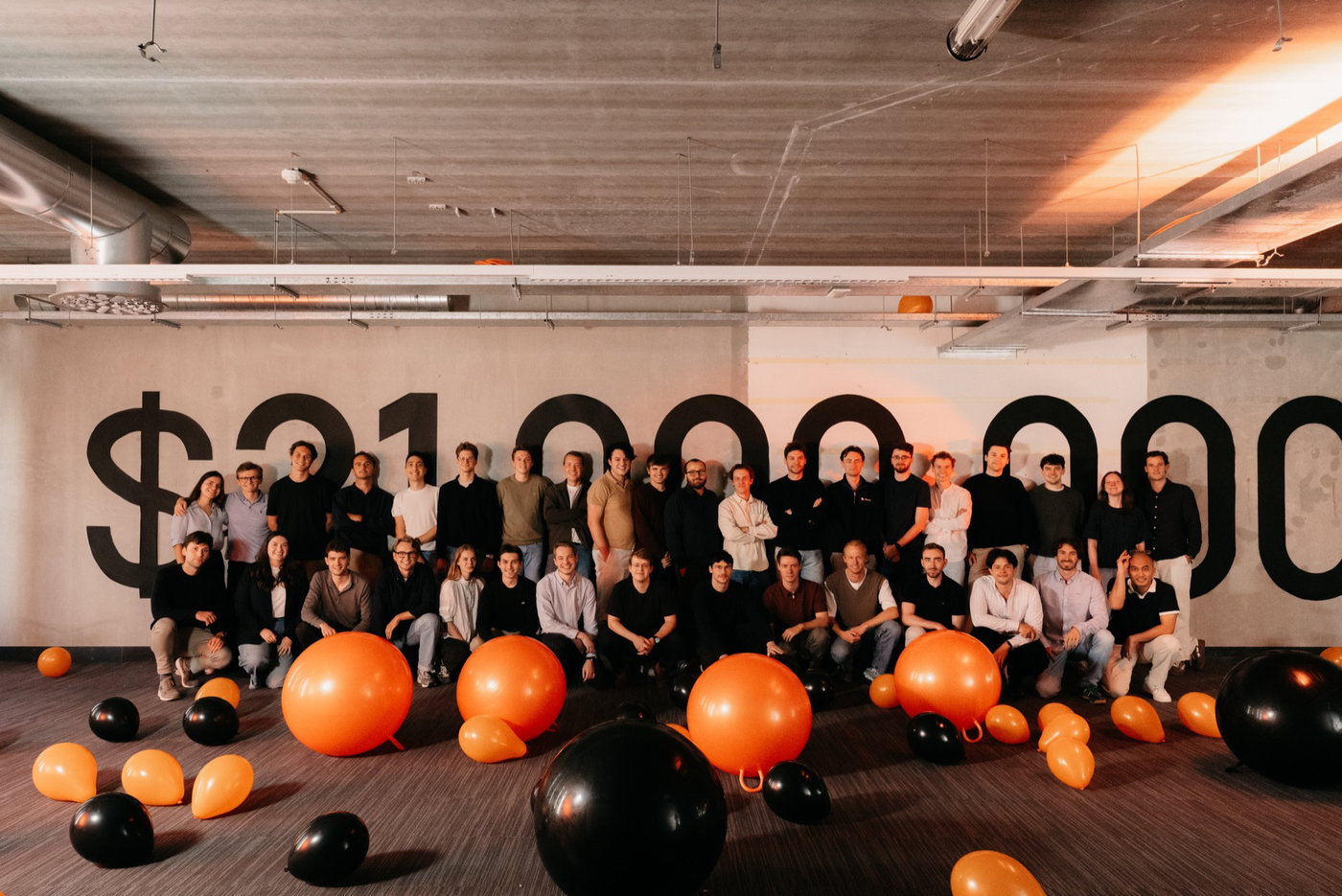 The Spott team gathered in its office in front of a painted 21 million dollar funding figure