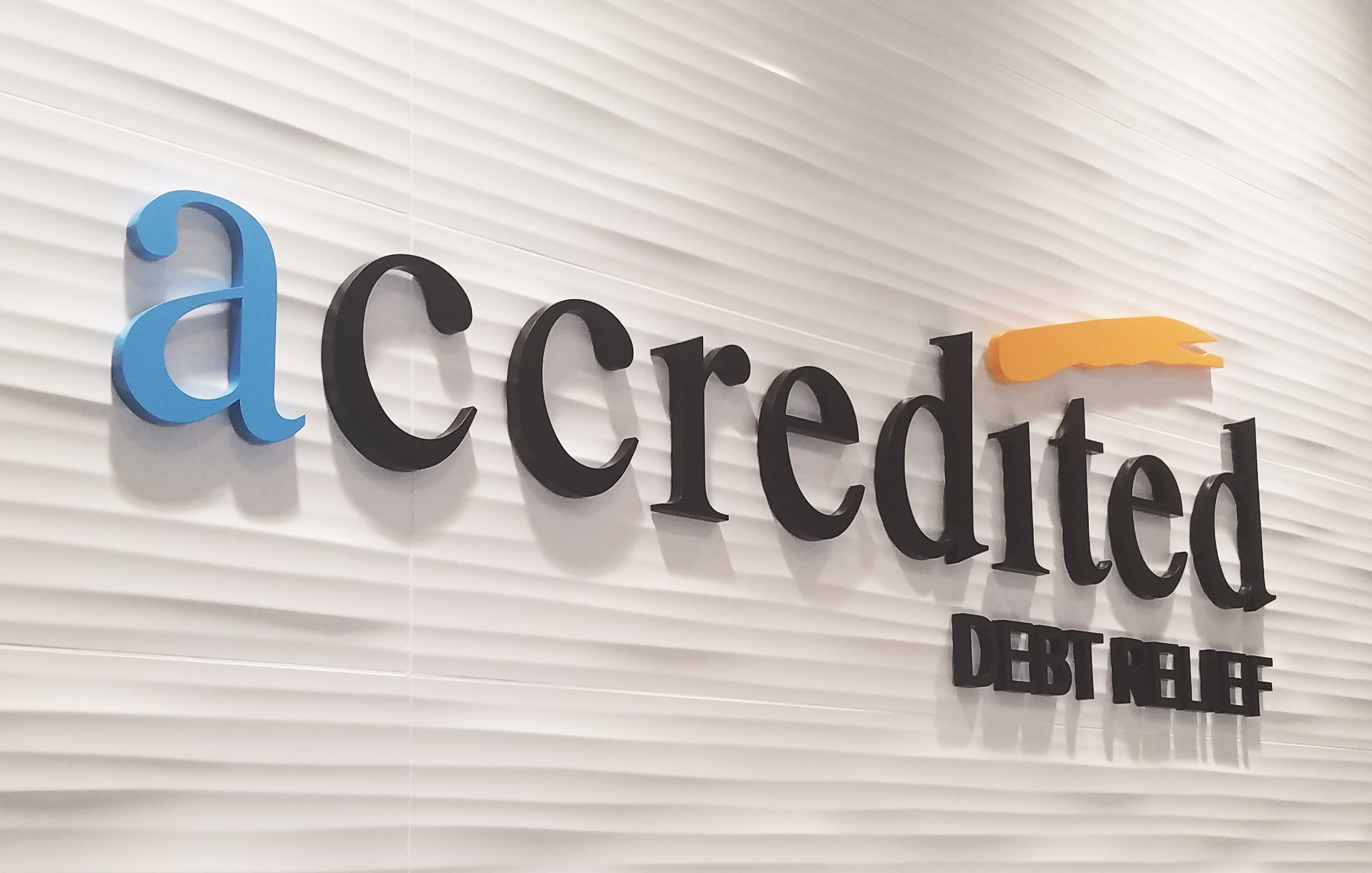Dimensional Accredited Debt Relief lettering casting shadows on a textured reception wall