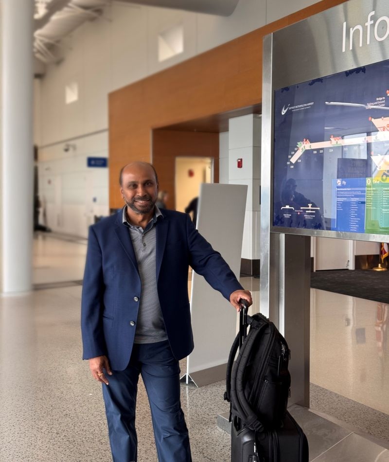 Sridhar Guduguntla standing beside his luggage at an airport before travelling to Hyderabad
