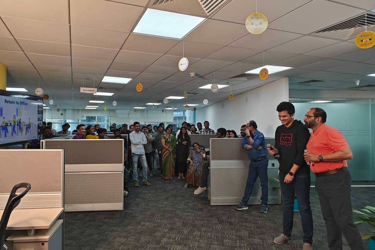 Srini Raj G, in an orange polo shirt, with colleagues during an office gathering at Gemini