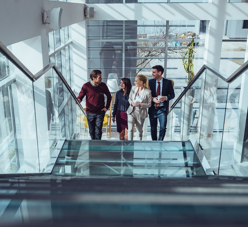 Illustrative photograph of four businesspeople walking together on an office staircase