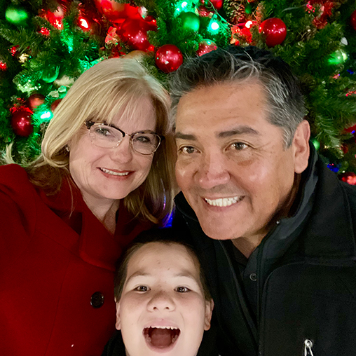 Stacey Nelson Smith with two companions in front of a decorated holiday tree