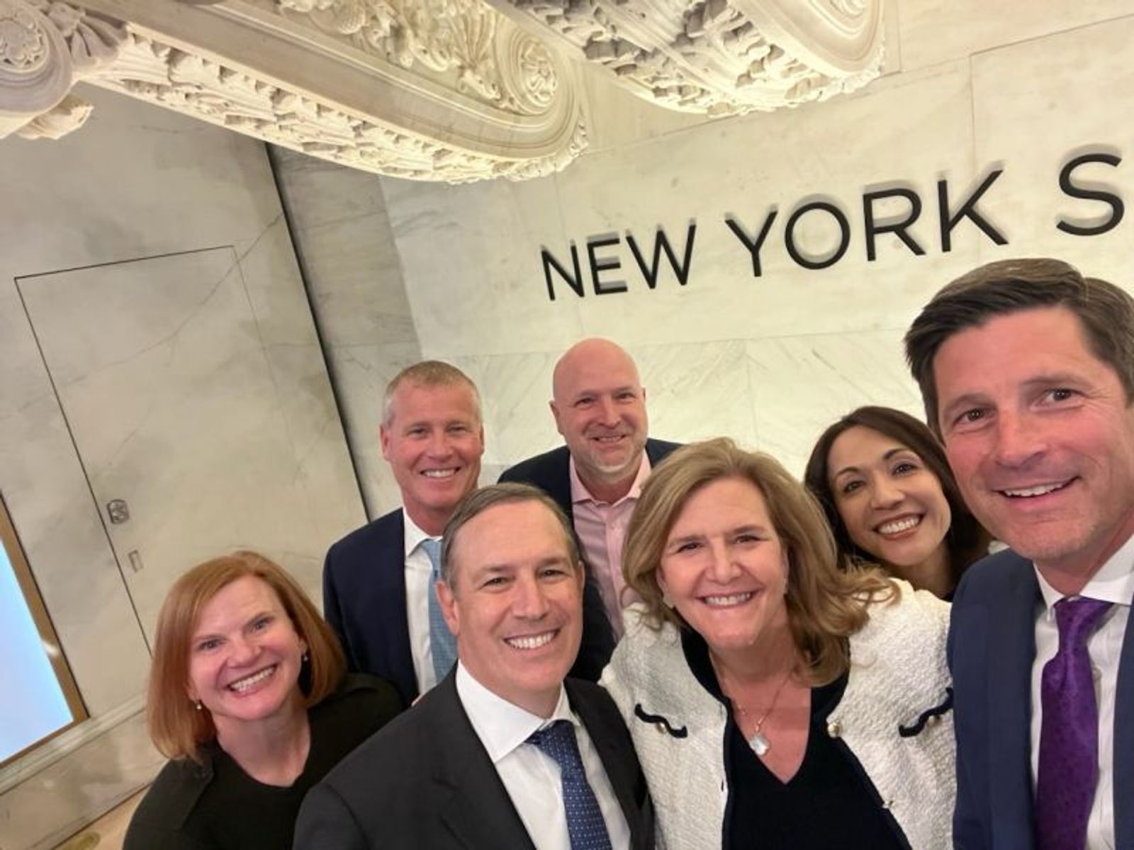 Stacy Hammond and Charles Schwab colleagues smiling together at the New York Stock Exchange