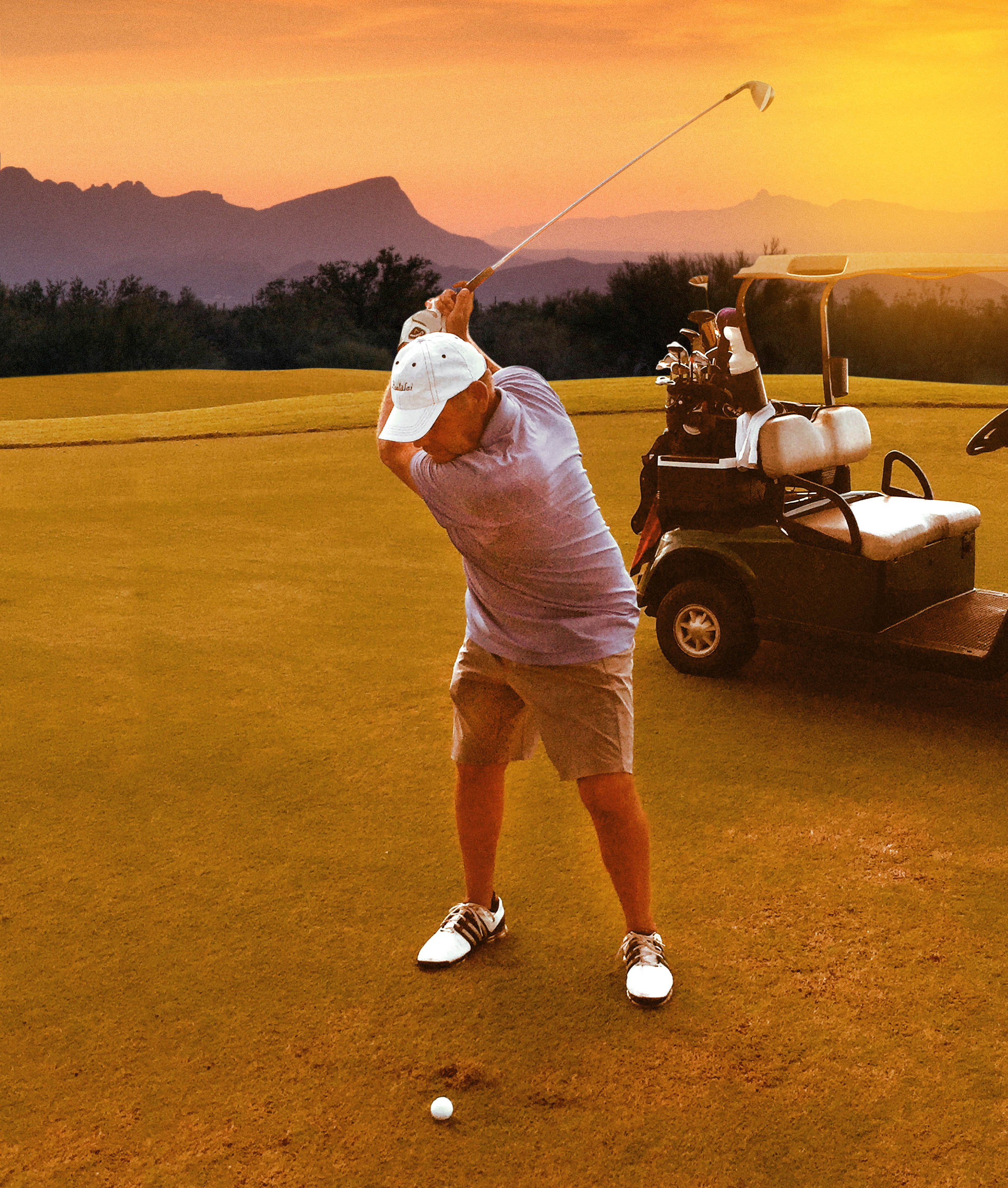 Stanford L. Kurland preparing a golf swing beside a golf cart in warm evening light