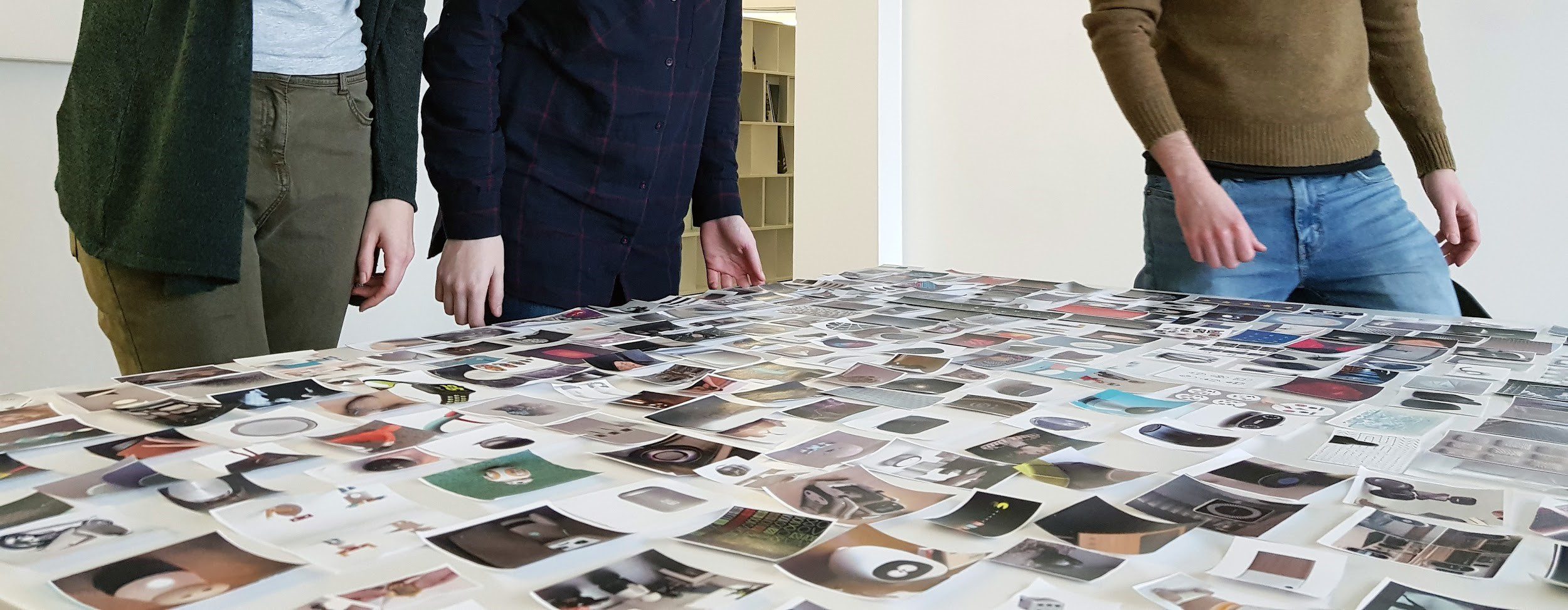 Design team members standing around a table covered with visual references during the NOMI project