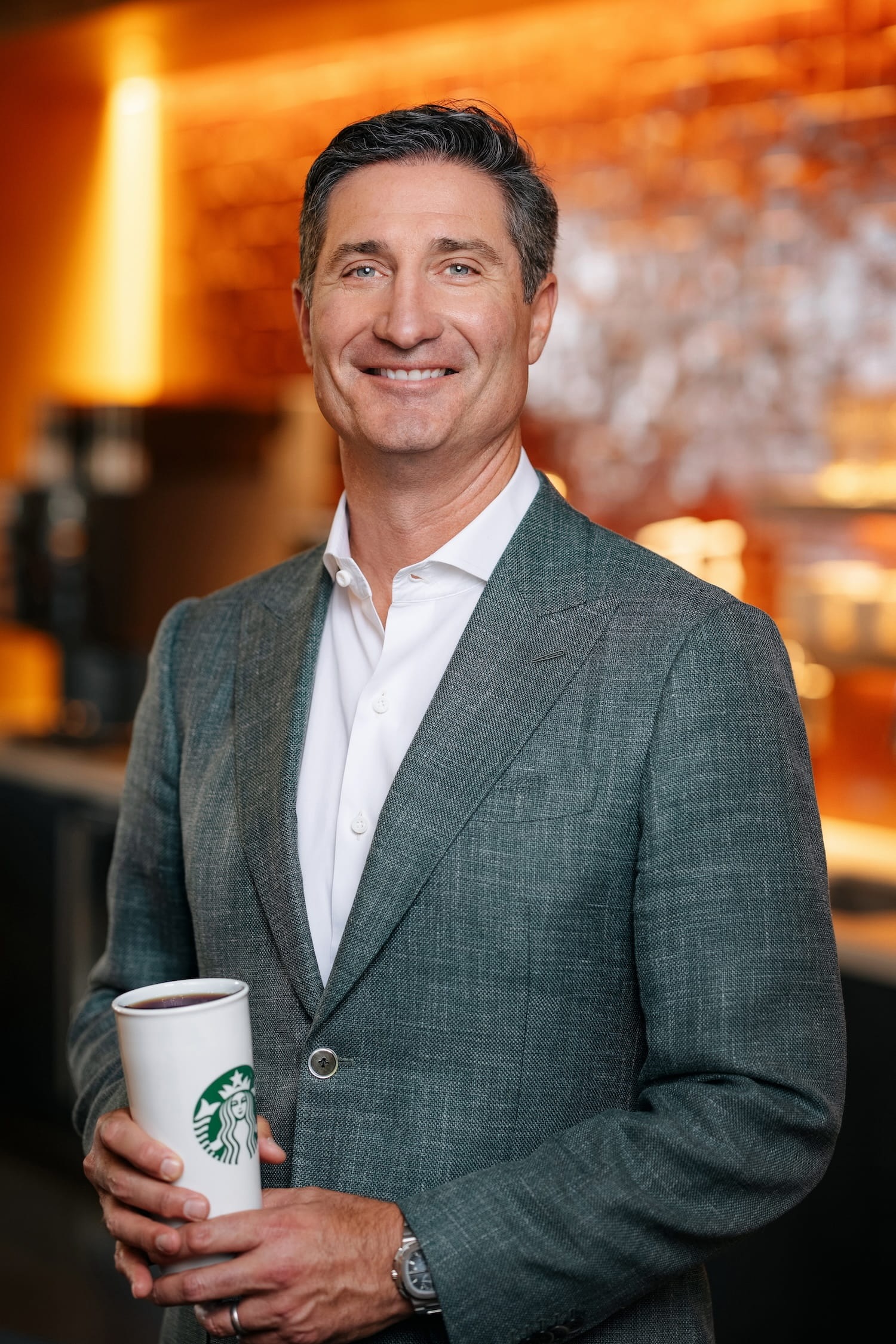 Starbucks chairman and chief executive Brian Niccol holding a paper coffee cup