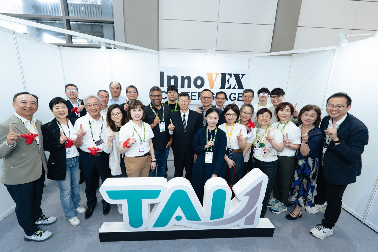 TAI1 participants and partners gather behind a large TAI1 sign at InnoVEX