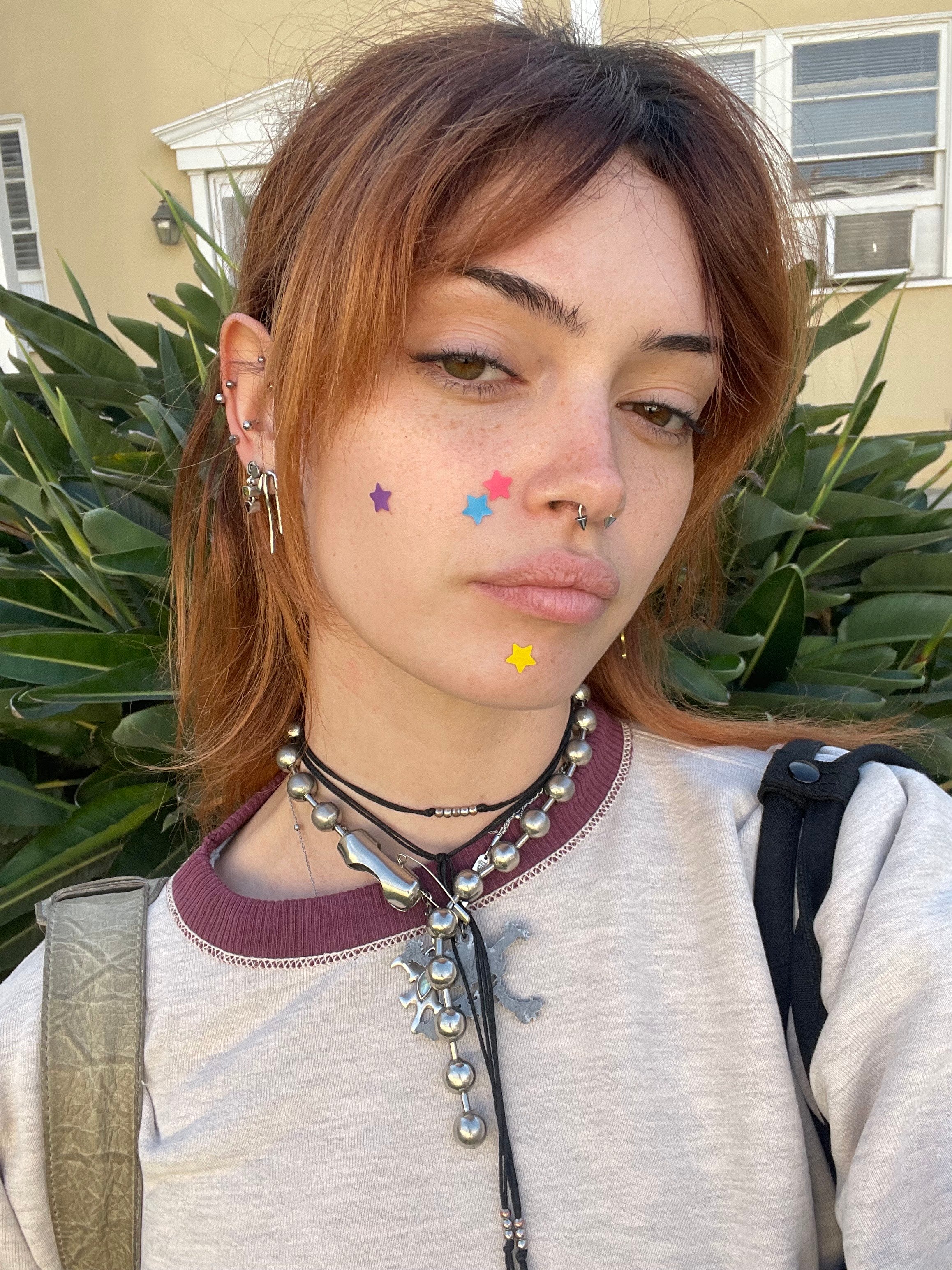 Person outdoors wearing purple, blue, pink and yellow Starface patches