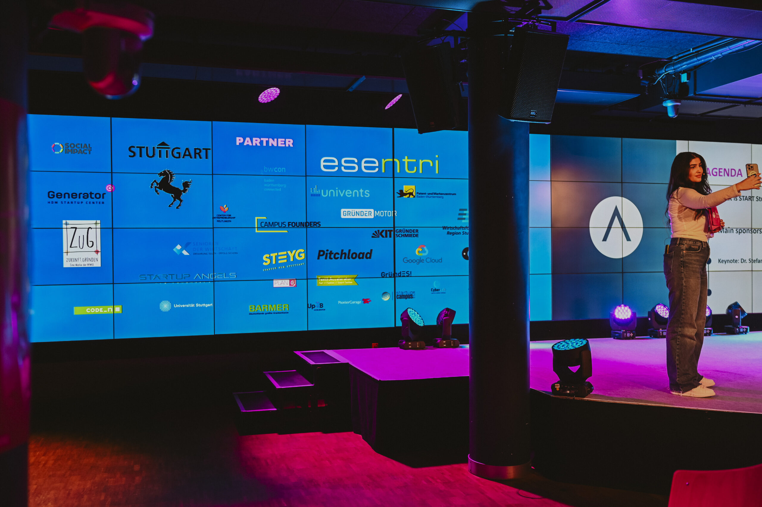 A START Stuttgart event host onstage beside a screen displaying event partners