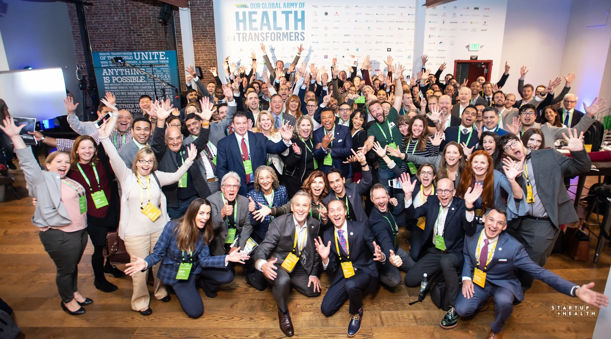 StartUp Health community members gathered together, smiling and raising their hands
