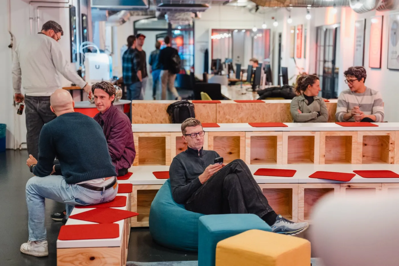 People talking in pairs and using a phone in an open SIB community area